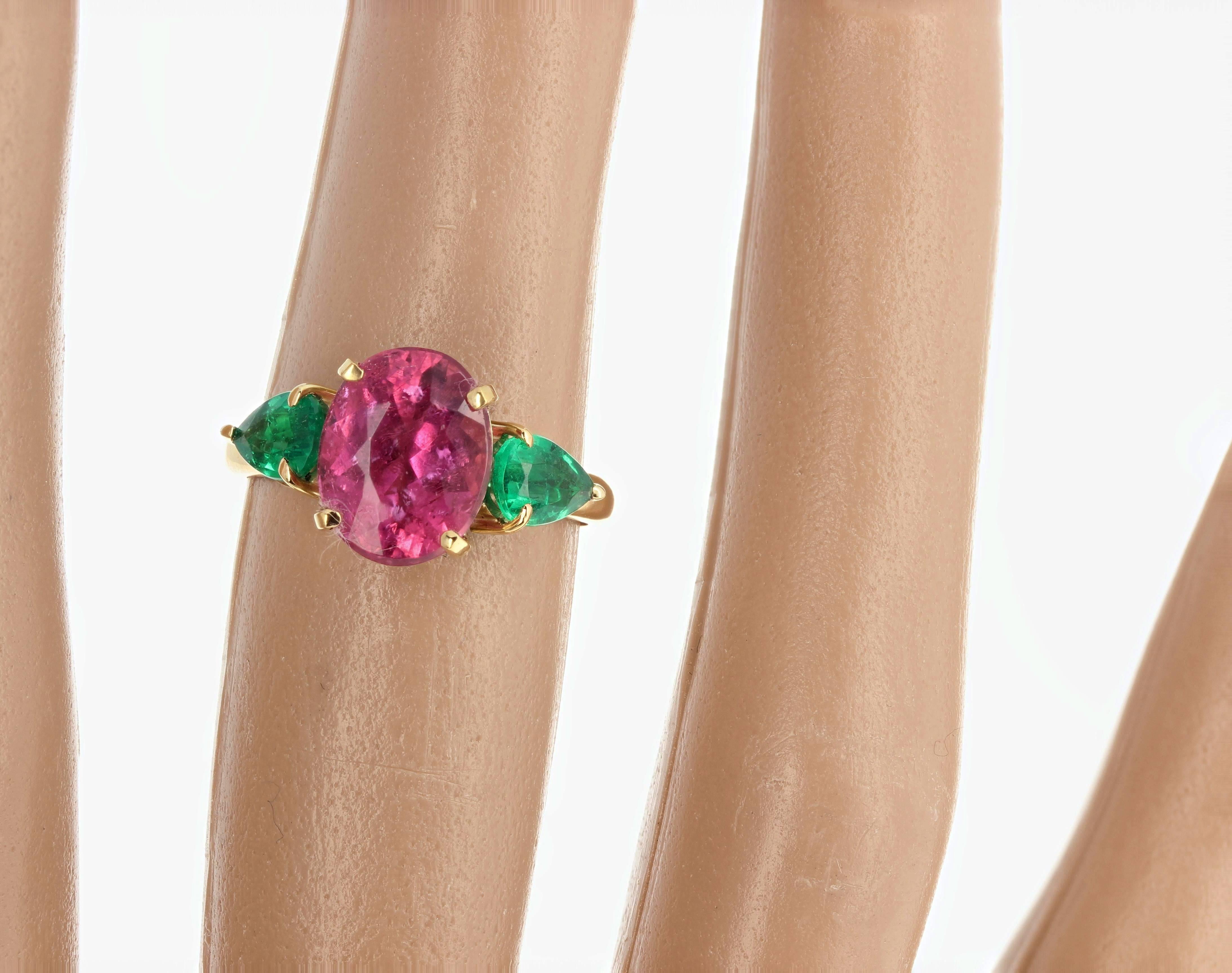 Deep brilliant pink clear 2.71 carat Tourmaline (10 mm x 8 mm) enhanced with two pear cut emerald side stones (4.5 mm x 6 mm) set in a unique handmade 18 Kt yellow gold ring size 6 (sizable).  Spectacular optical effect in the pink Tourmaline