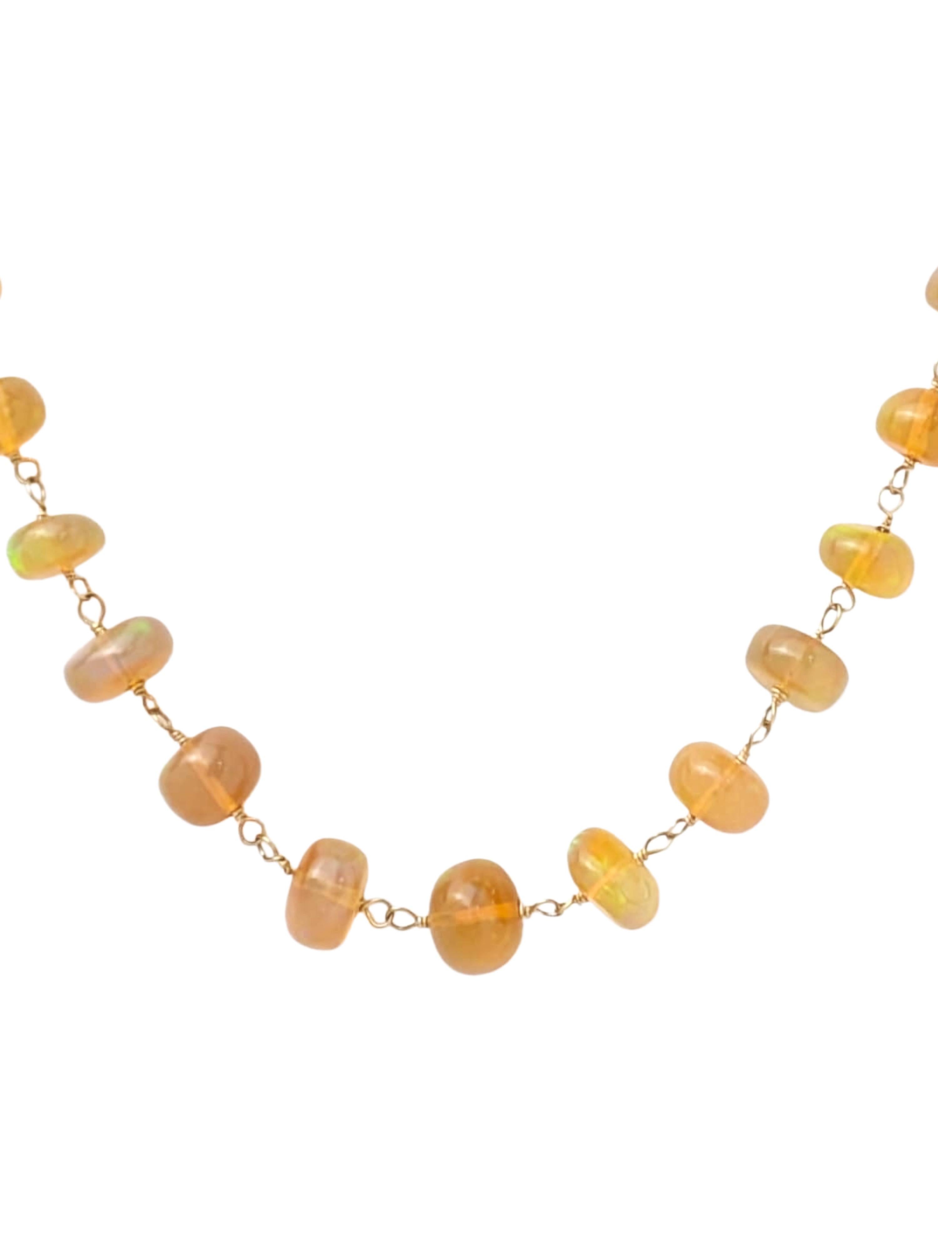 Un fil de couleur éthérée et d'artisanat doré. Ce collier de 27 pouces présente des perles d'opale éthiopienne rondes et brillantes, chacune animée par des éclairs de feu arc-en-ciel. Les opales sont reliées individuellement par un fil d'or jaune