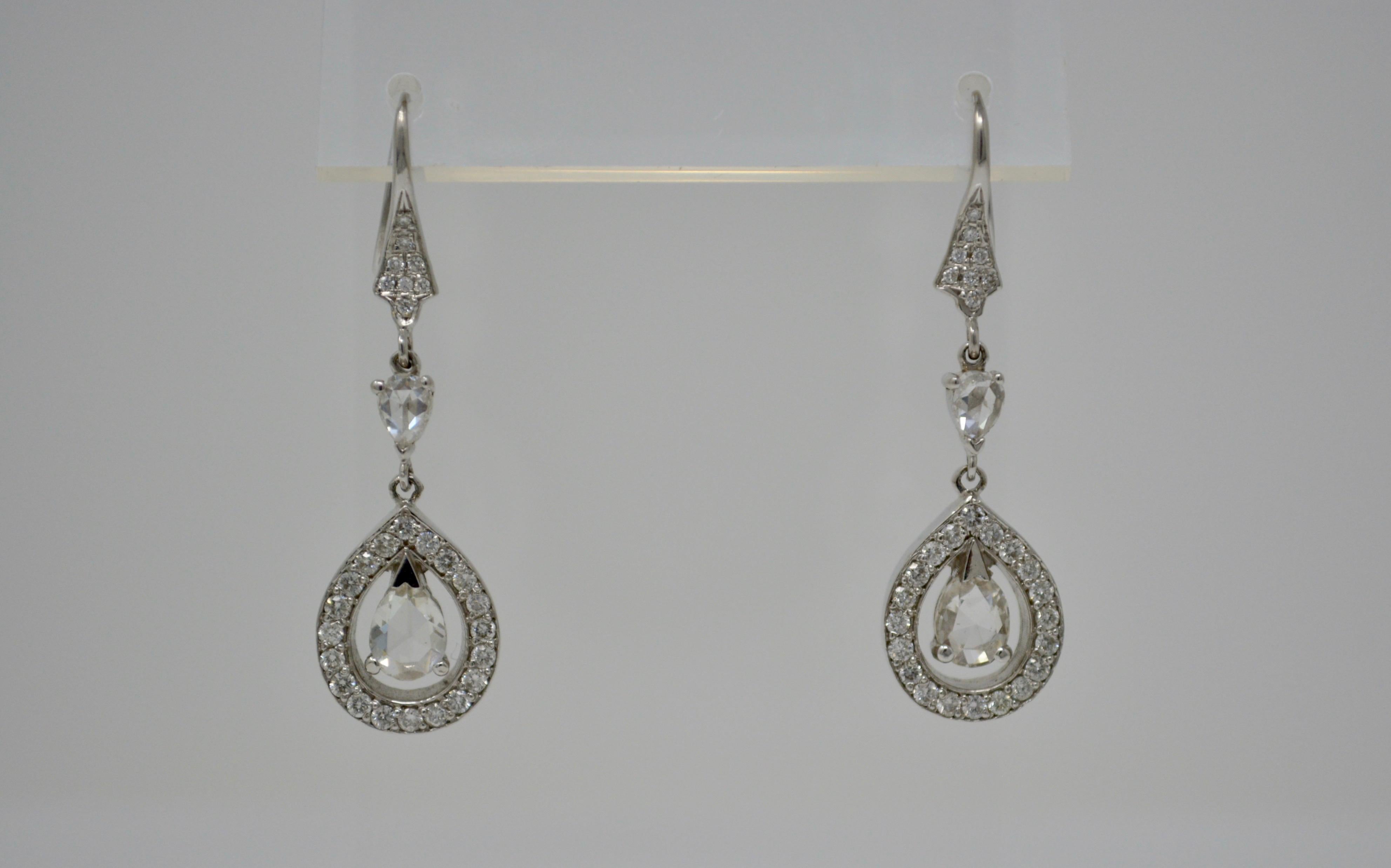 A unique pair of rose cut diamond drop earrings features two big pear shape rose cut diamonds with G-H color with VS clarity set in the center of diamond studded pear shape frame which is suspended by two small rose cut pear shape diamond with F-G