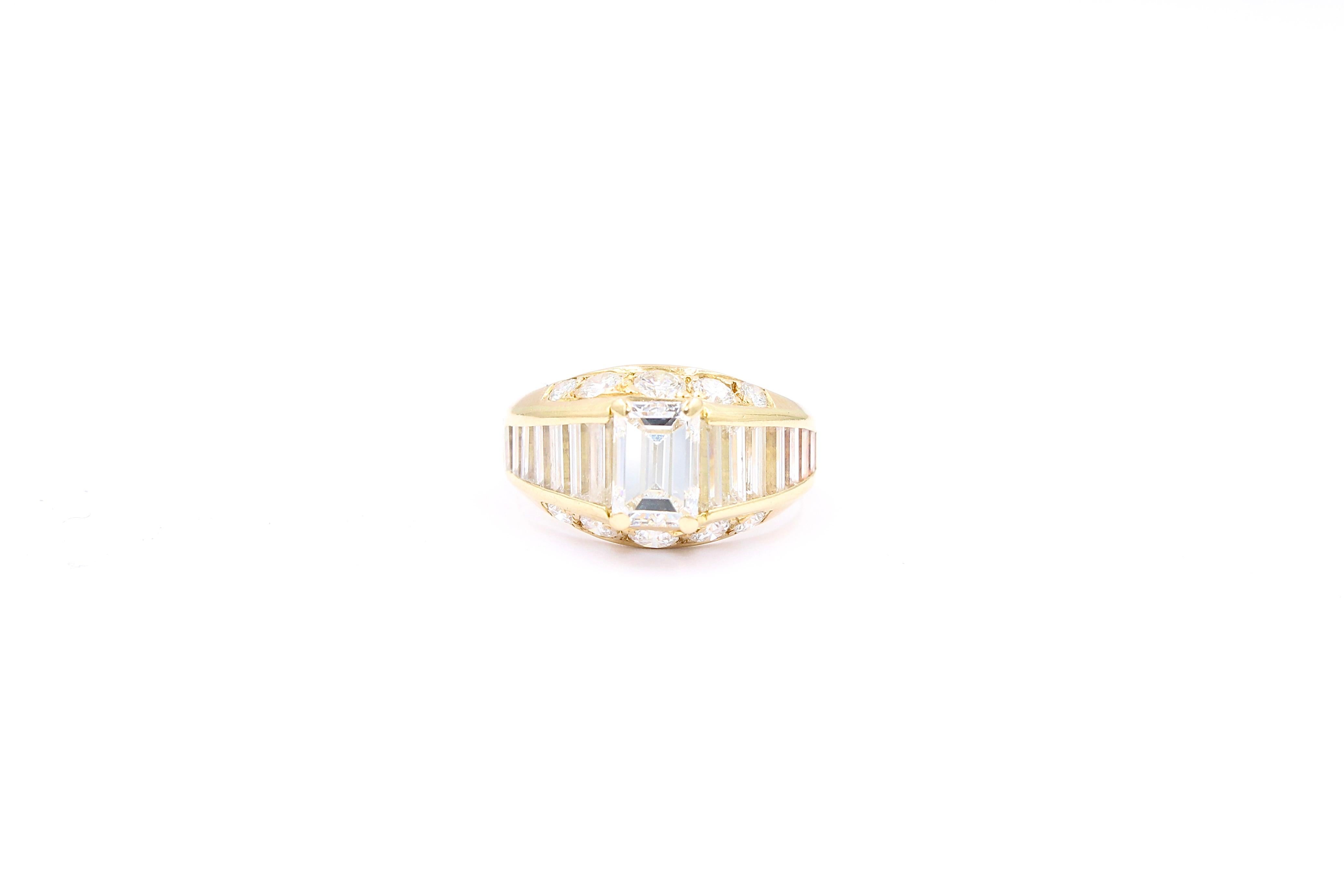 Vintage Ring made of Yellow gold 18 Kt. and diamonds. 

The ring is set with a center emerald cut diamond of approximately 1.00 Carats (IGI Certified colorless color/ E-F - VS1 purity), 10 full cut diamonds for a total of approximately 0.50 Carats