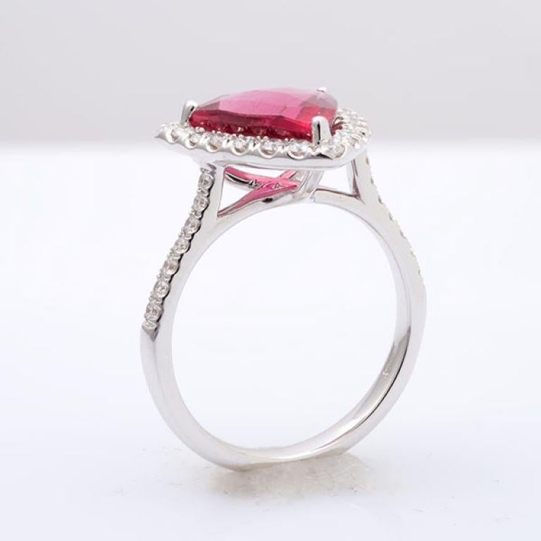 The Rubellite ring features a stunning, trillion-shaped gemstone in a prong setting with a diamond halo, set in durable 14K white gold. This versatile ring is ideal for engagement or as a wedding ring, offering a unique pop of color with the vibrant
