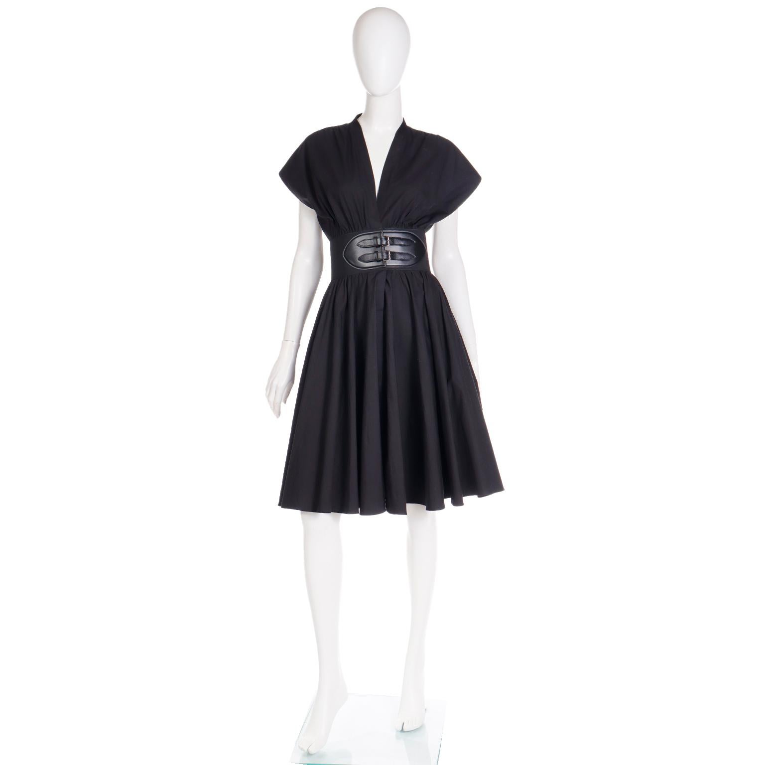 This easy to wear, modern Alaia dress is in a crisp black cotton poplin and features a built in signature Alaia belt with leather trim. The dress has a fun, full skirt, a deep v bodice and slightly capped sleeves. There are side slit pockets and the