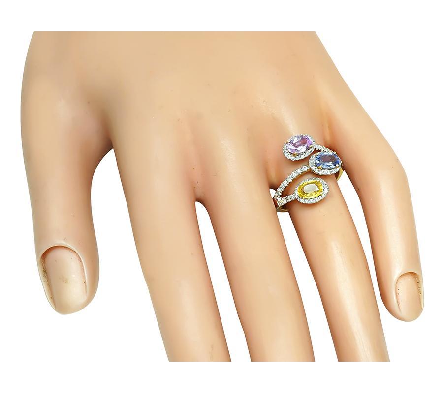 Se trata de un fabuloso anillo de oro amarillo y blanco de 14 quilates. El anillo está engastado con preciosos zafiros multicolores de talla ovalada que pesan aproximadamente 2.70 ct. Los zafiros están acentuados por brillantes diamantes de talla