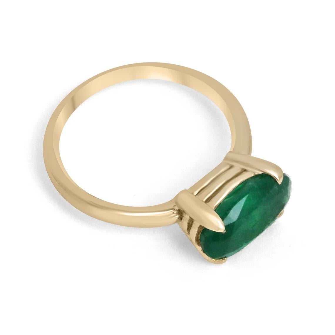 Displayed is a dark forest green emerald, solitaire, oval cut ring in 18K yellow gold. This gorgeous solitaire ring carries a full 2.71-carat emerald in a sleek four-prong setting. The emerald has very good clarity and remarkable luster. This