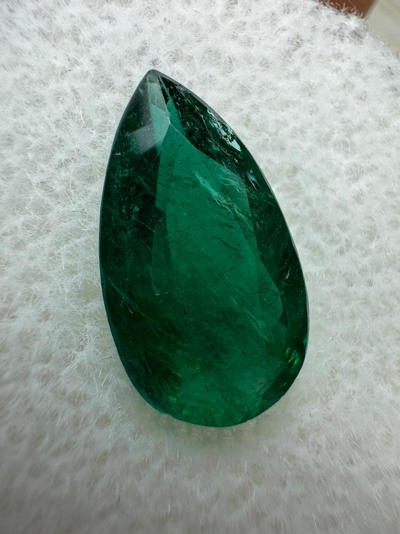 Stone: Emerald
Weight: 2.72-carats
Shape: Pear Cut
Clarity: Transparent
Luster: Very Good
Color: Dark Green
Measurements: 13.83mm x 7.63mm x 4.37mm
Geographic Origin: Zambia
Treatment: Natural, Oiling

Comments: Due to their growth conditions in