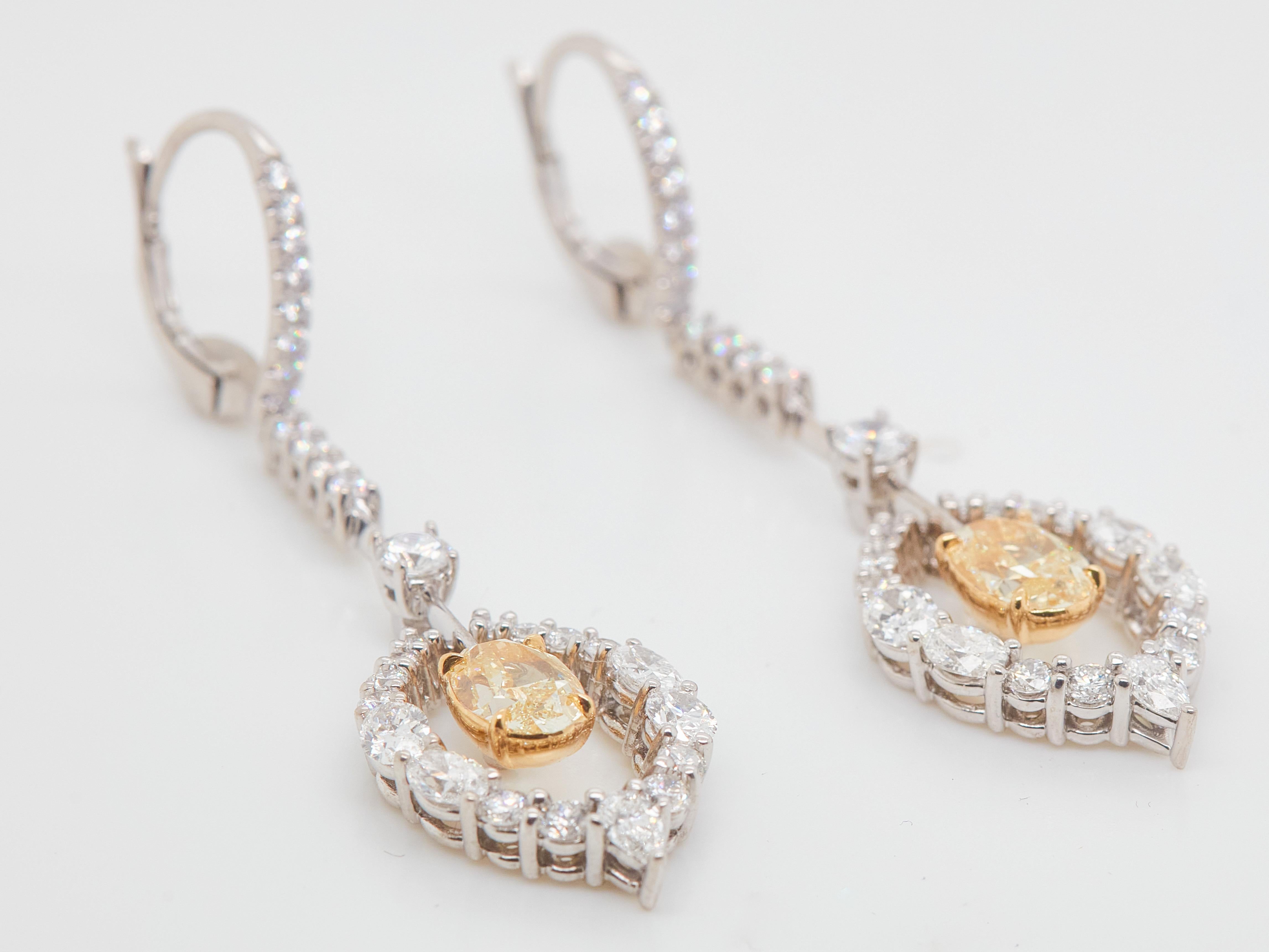 A stunning matched pair of 2.72 carat center stones, GIA Certified natural Fancy Light Yellow diamonds. 
These elegant chandelier drop earrings showcase 1.39 carat and 1.33 carat Fancy Light yellow oval-cut diamonds that surrounded by approximately