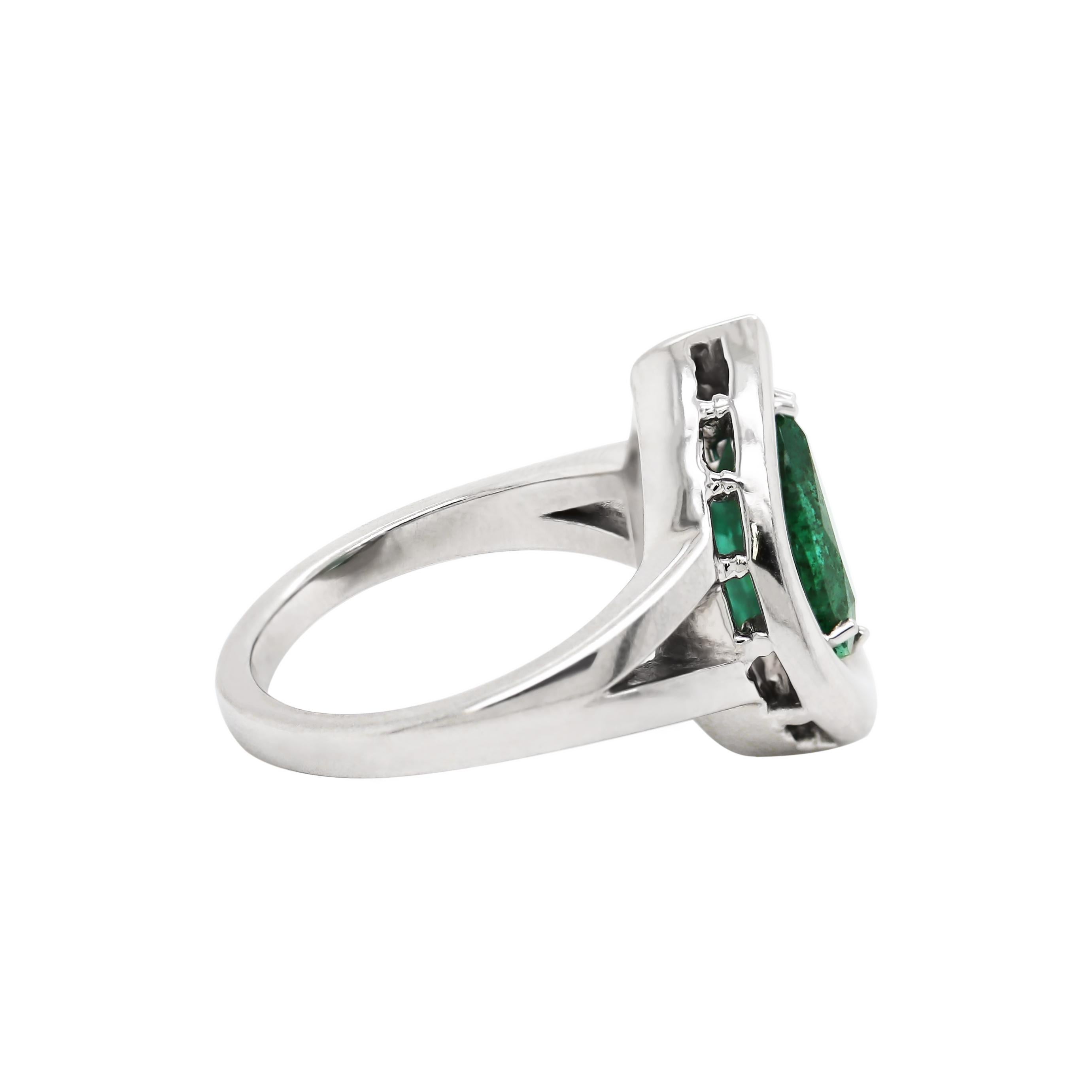 This hand made ring features a beautiful pear shaped emerald weighing 2.72ct, mounted in a six claw, open back setting. The stone is set in the centre of a platinum tear drop frame mounted on a solid split shoulder shank. Hallmarked, Platinum. UK