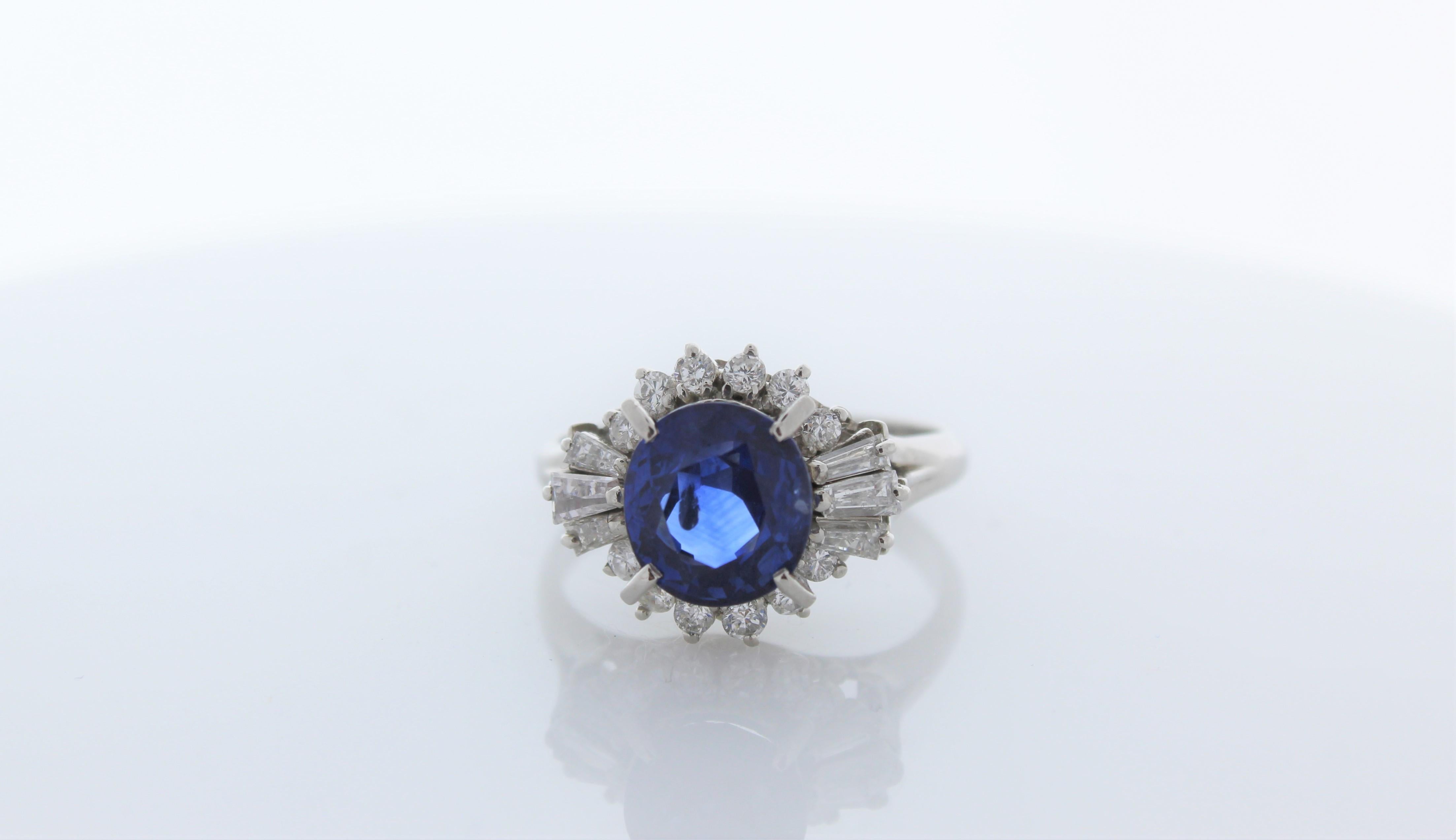 This is a 2.72 carat cushion cut blue sapphire. The gem source is Sri Lanka; its color is royal blue and it is evenly distributed throughout the gem. Its luster and transparency is superb. Sparkling round brilliant cut diamonds frame this sapphire