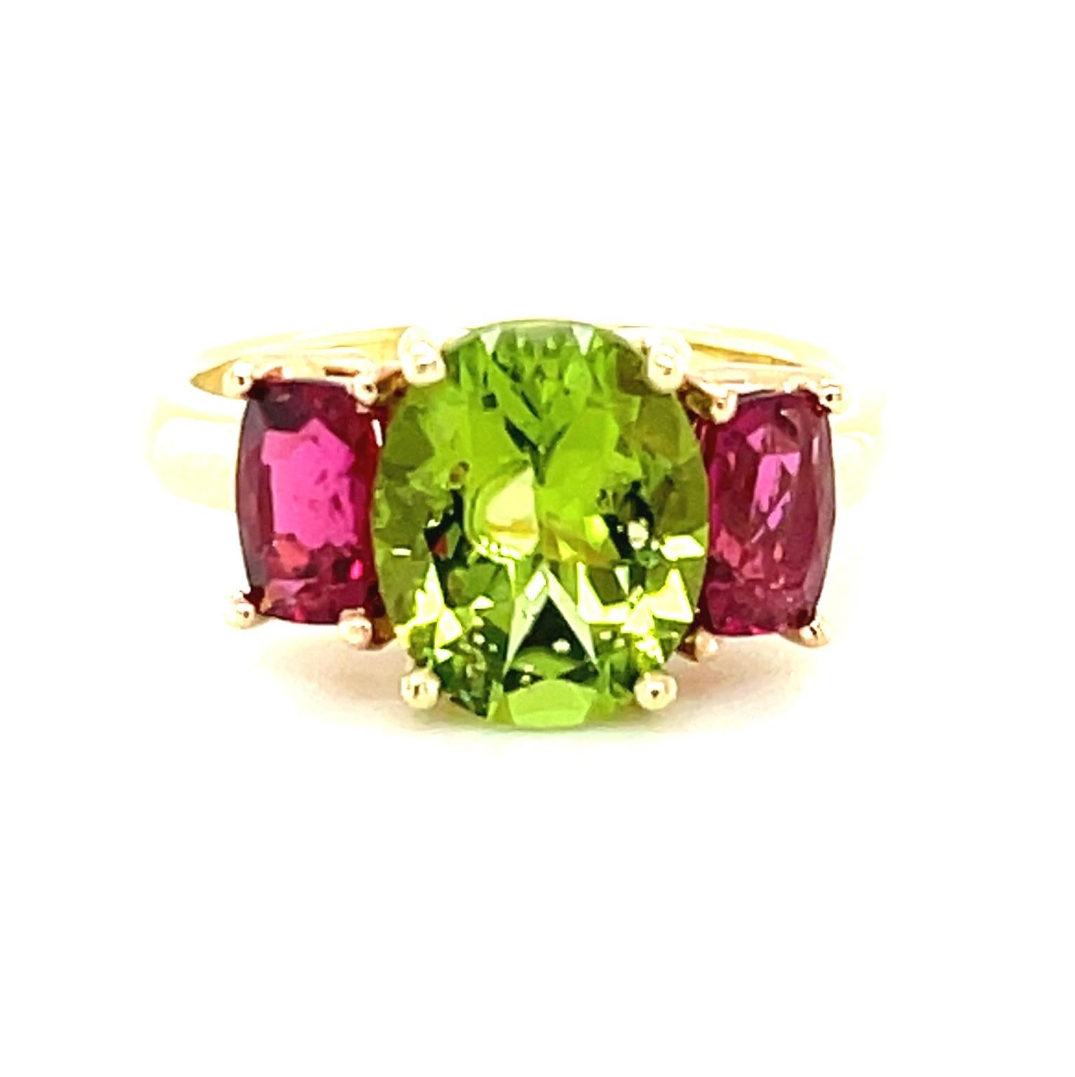 Featuring a bright and cheerful pairing of spring green peridot and vibrant fuchsia-pink tourmalines, this luscious ring is guaranteed to put a smile on your face! The peridot is a beautifully brilliant grass green oval weighing 2.73 carats and the