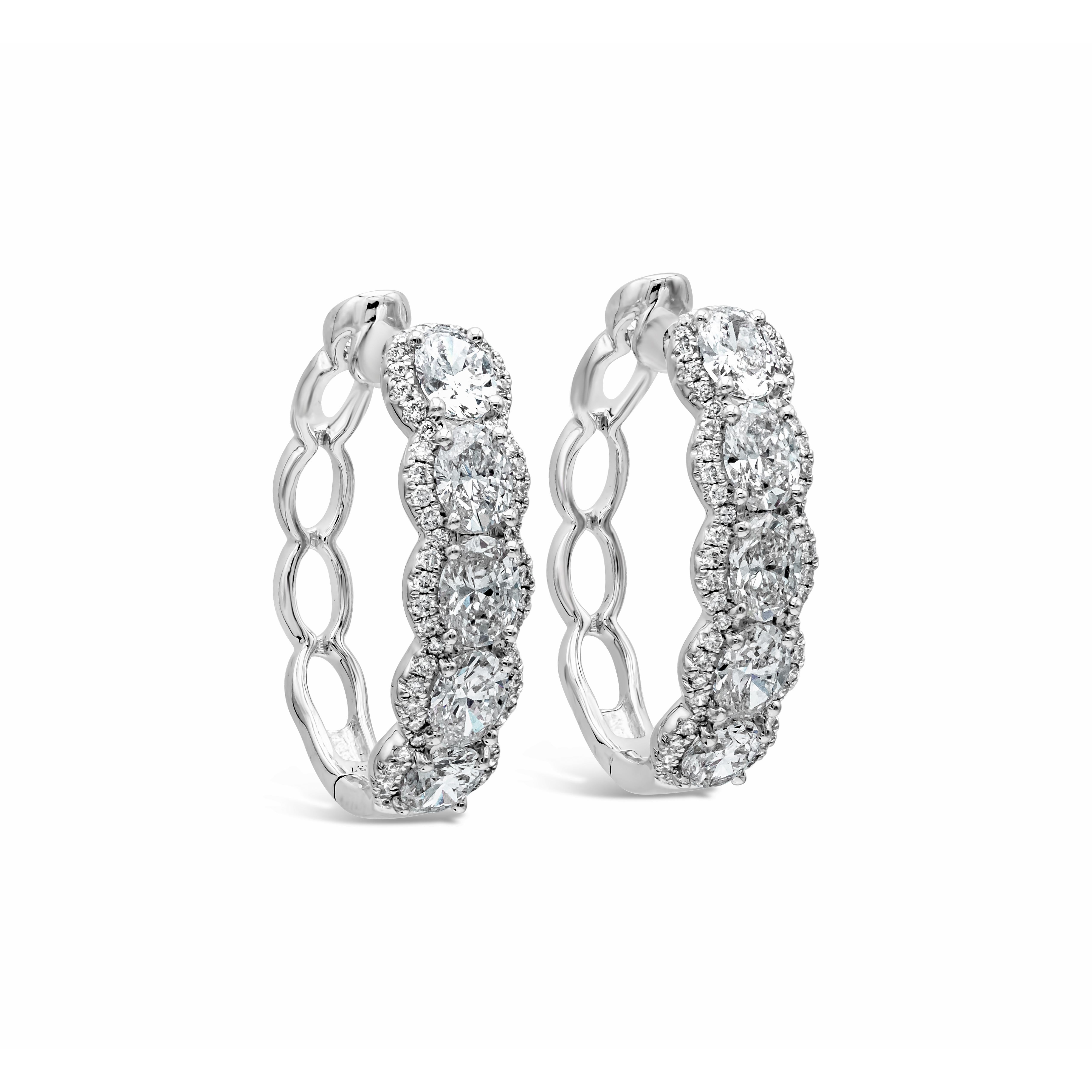 This beautiful pair of oval shape hoop earrings showcases five oval cut diamonds on each earring. Outlined on two sides by a row of brilliant round diamonds. Diamonds weigh 2.73 carats total. Made in 18k white gold. 

Style available in different