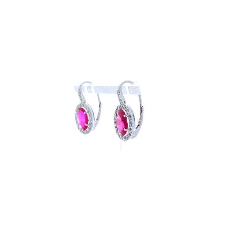 Elegant and timeless, these fashionable earrings feature 2.75 carat total of gorgeous and perfectly matched, ravishing red Thai rubies. They are the perfect red, evenly distributed through the gem. They are surrounded by sparkling diamond halos that
