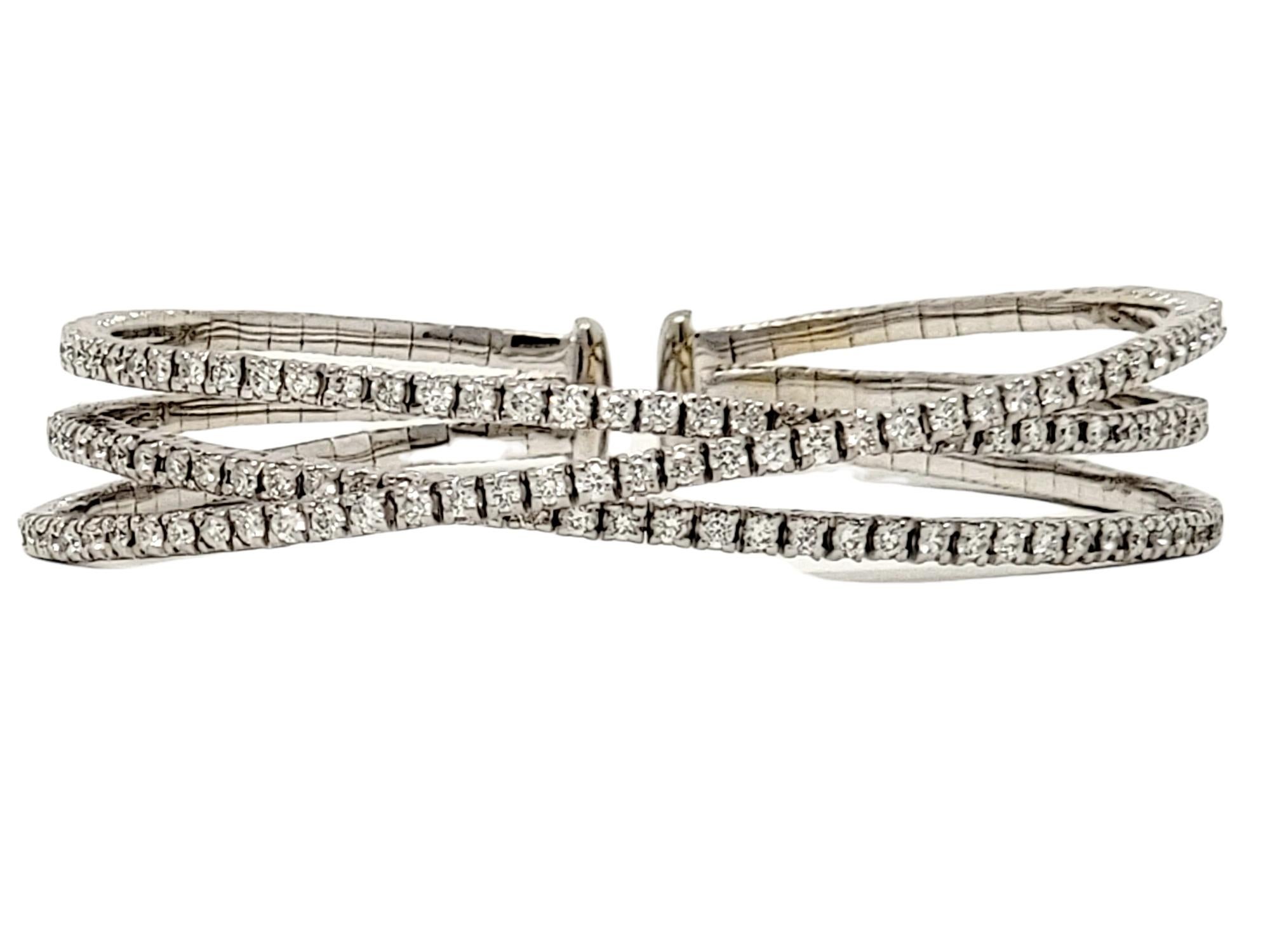 Breathtaking modern diamond cuff bracelet bursting with sparkle. This incredible bracelet is made of polished 18 karat white gold and features 3 individual rows set in an open crisscross design. The narrow rows are all embellished with glittering