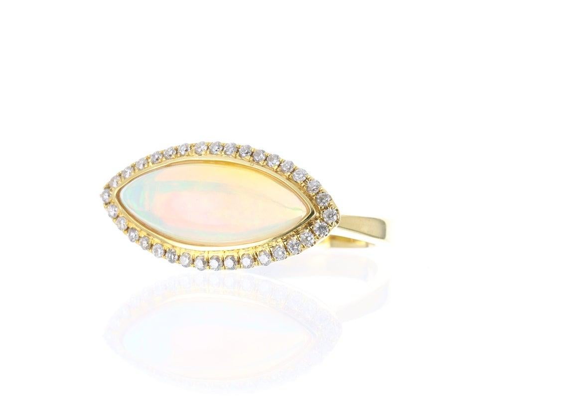 A one of kind, couture-inspired opal, and diamond East to West ring. Make it your engagement ring or right-hand ring, it is the perfect statement piece. The focal point in this beautiful ring is a natural, solid opal filled with illuminating rays of