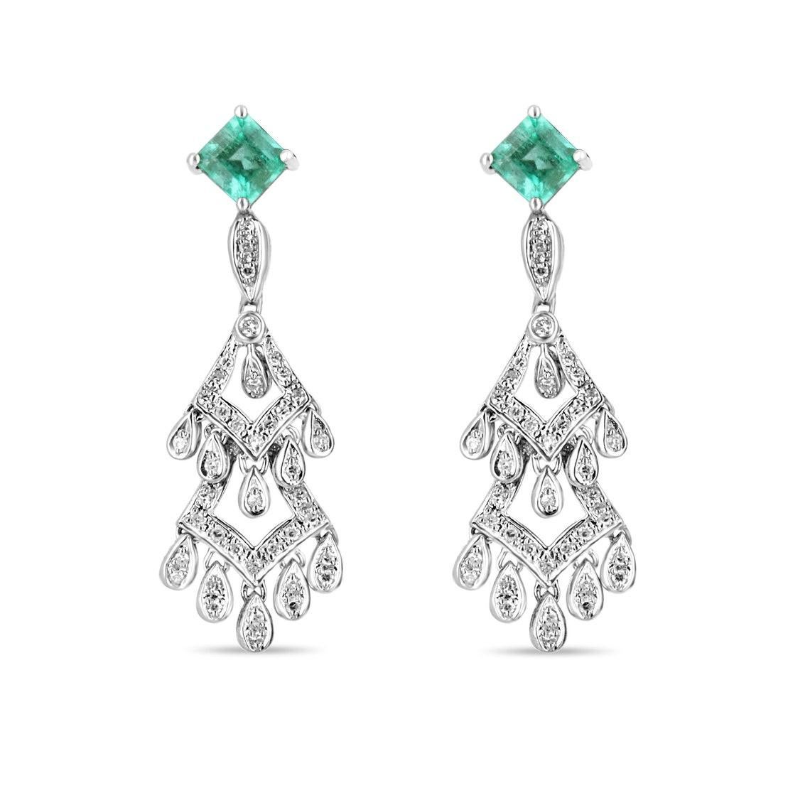 A modern pair of emerald and diamond chandelier earrings. Fashioned in pure, 14K white gold, earth-mined Colombian emeralds are handset in a prong setting, delicately kissing the earlobe. These natural gems have very beautiful luster, clarity, and