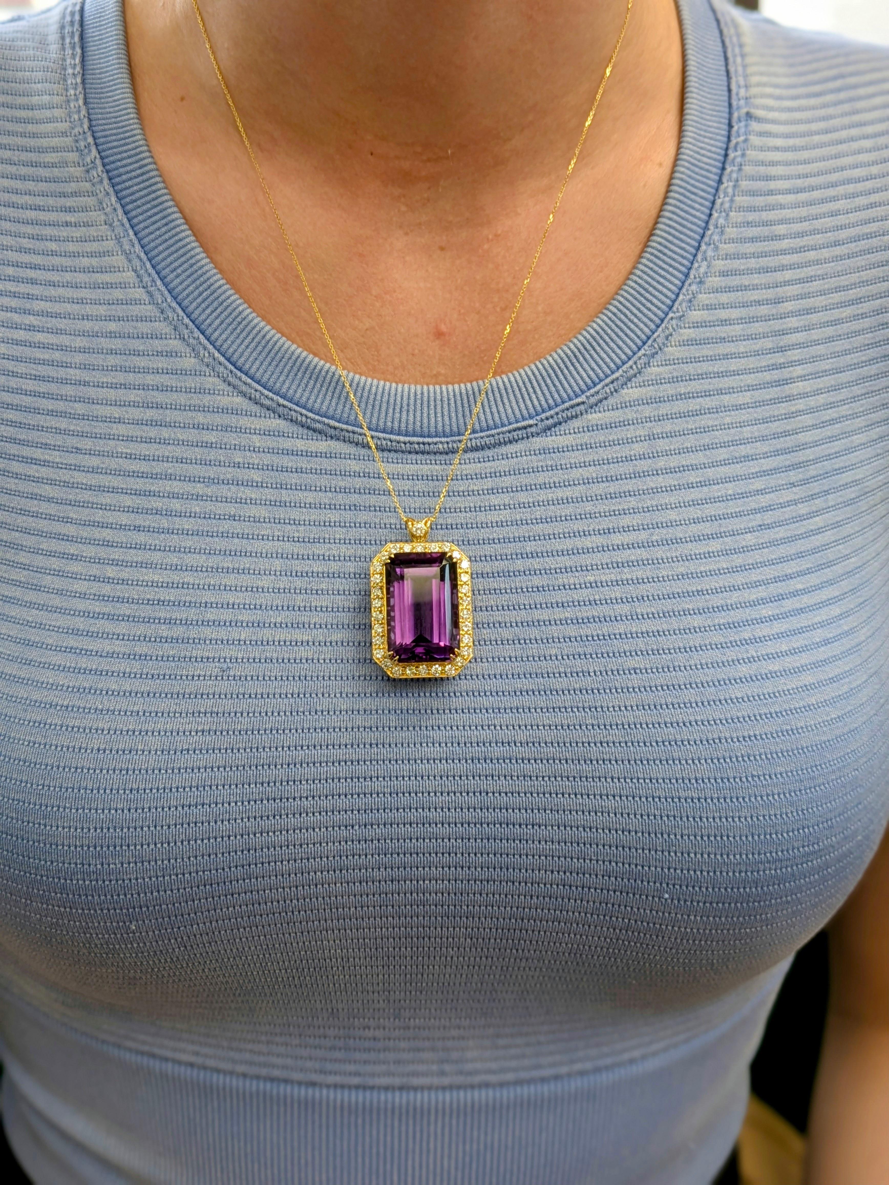 Questo pendente di grande effetto mette in mostra una vivida ametista taglio smeraldo da 22 carati (27,5x18,5 mm), avvolta da una scintillante aureola di diamanti estratti dalla terra. Realizzato con maestria in oro giallo massiccio 14 carati, è un