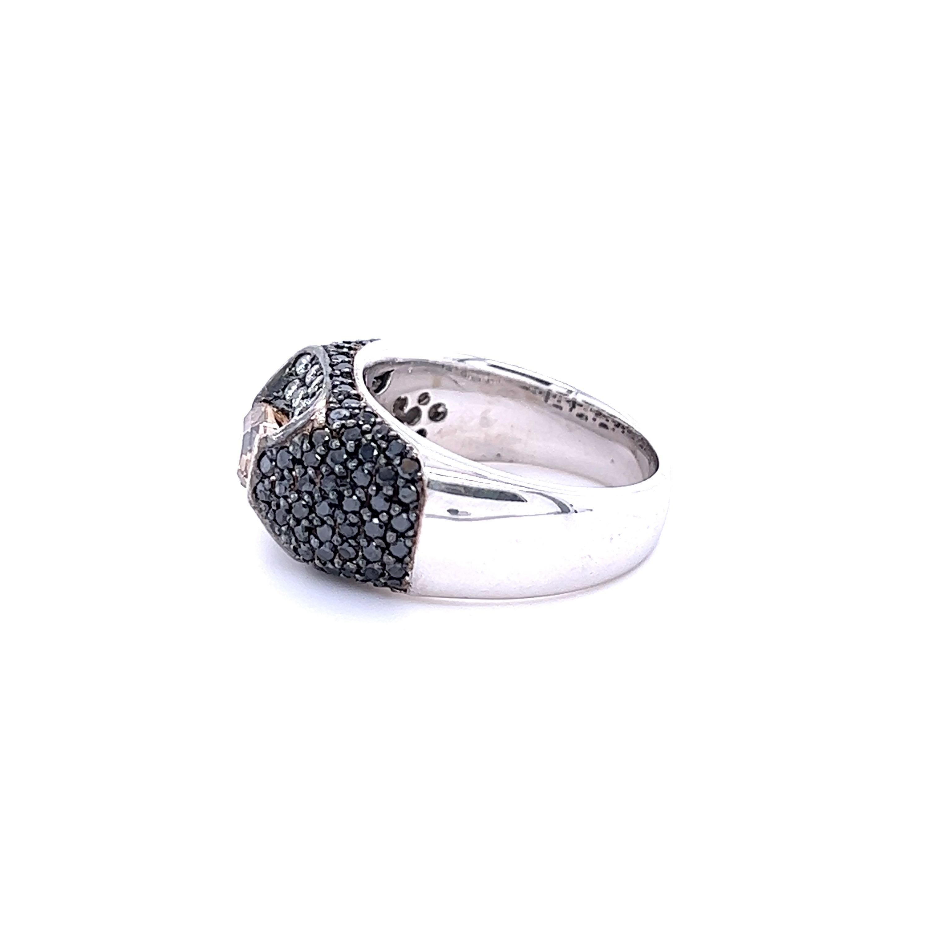 This cocktail ring has a 1.27 carat Oval Cut Natural Champagne Diamond that measures at approximately 7 mm x 5 mm. It is surrounded by 18 Natural Round Cut White Diamonds that weigh 0.31 carats and 96 Natural Round Cut Black Diamonds that weigh 1.18