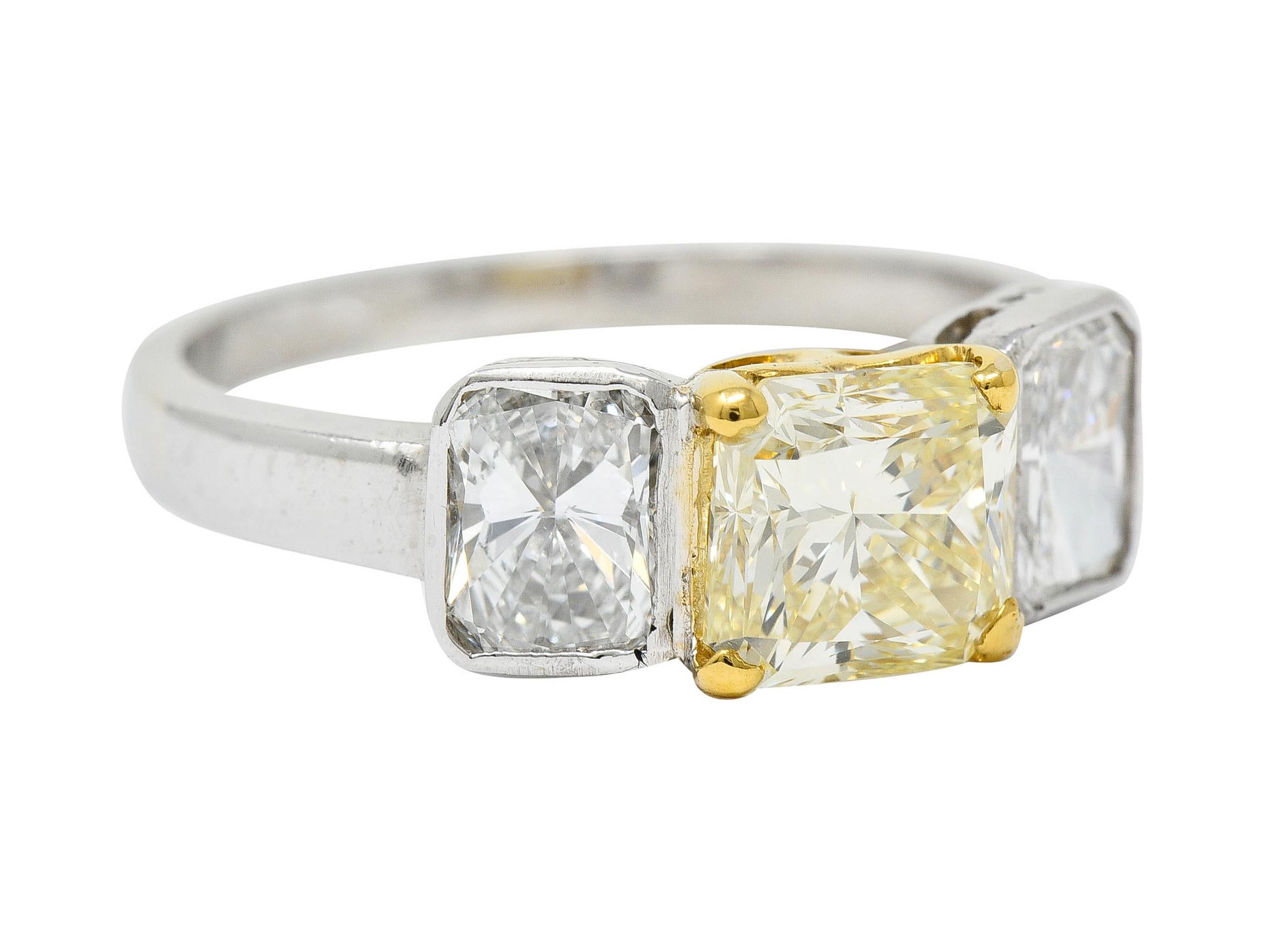 Three stone ring centers a radiant cut fancy colored diamond weighing approximately 1.60 carats

Basket set in yellow gold and features fancy yellow color with VS clarity

Flanked by two radiant cut diamonds - bezel set in platinum

Weighing in
