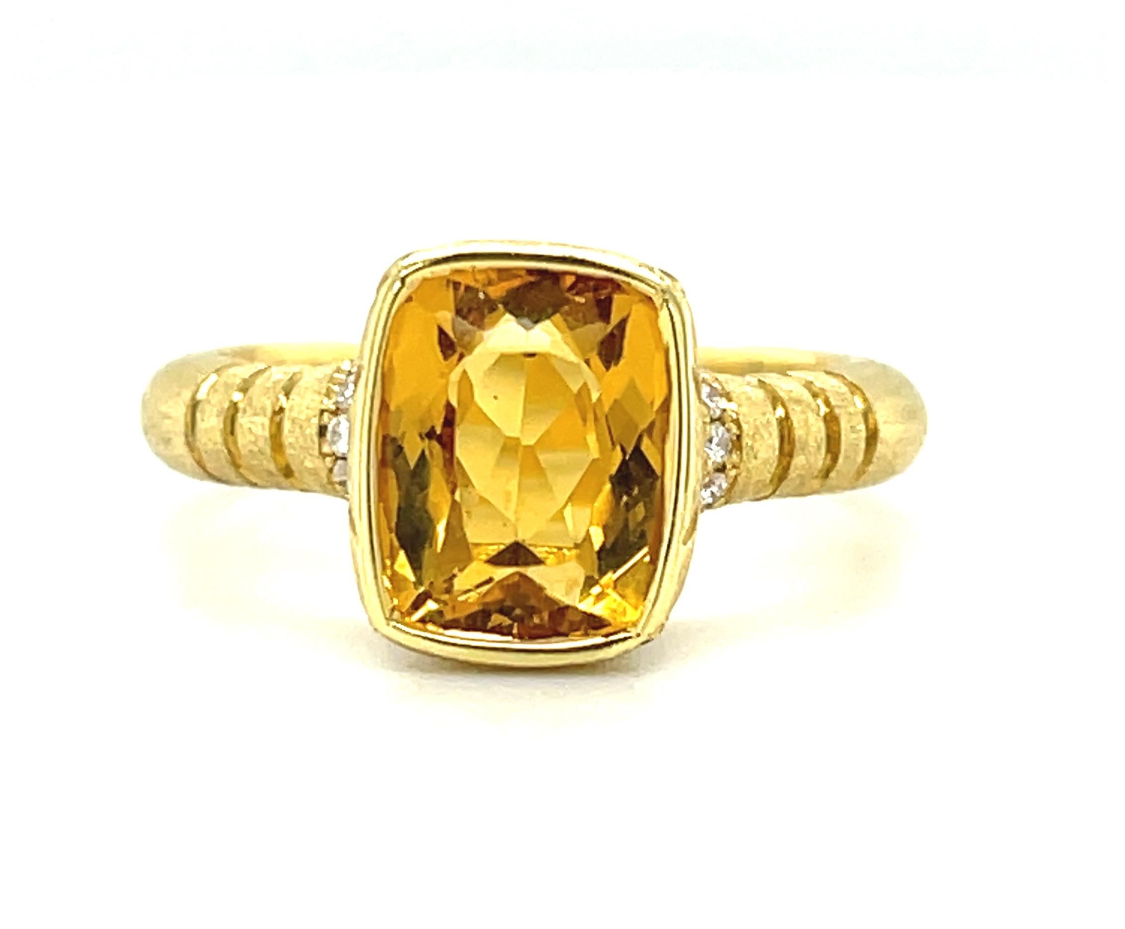 Featuring a golden honey-colored yellow beryl, this handcrafted ring was exquisitely made in 18k yellow gold which emphasizes the rich color of the center stone. The cushion-cut yellow beryl is bezel set with brilliant white diamonds adorning the