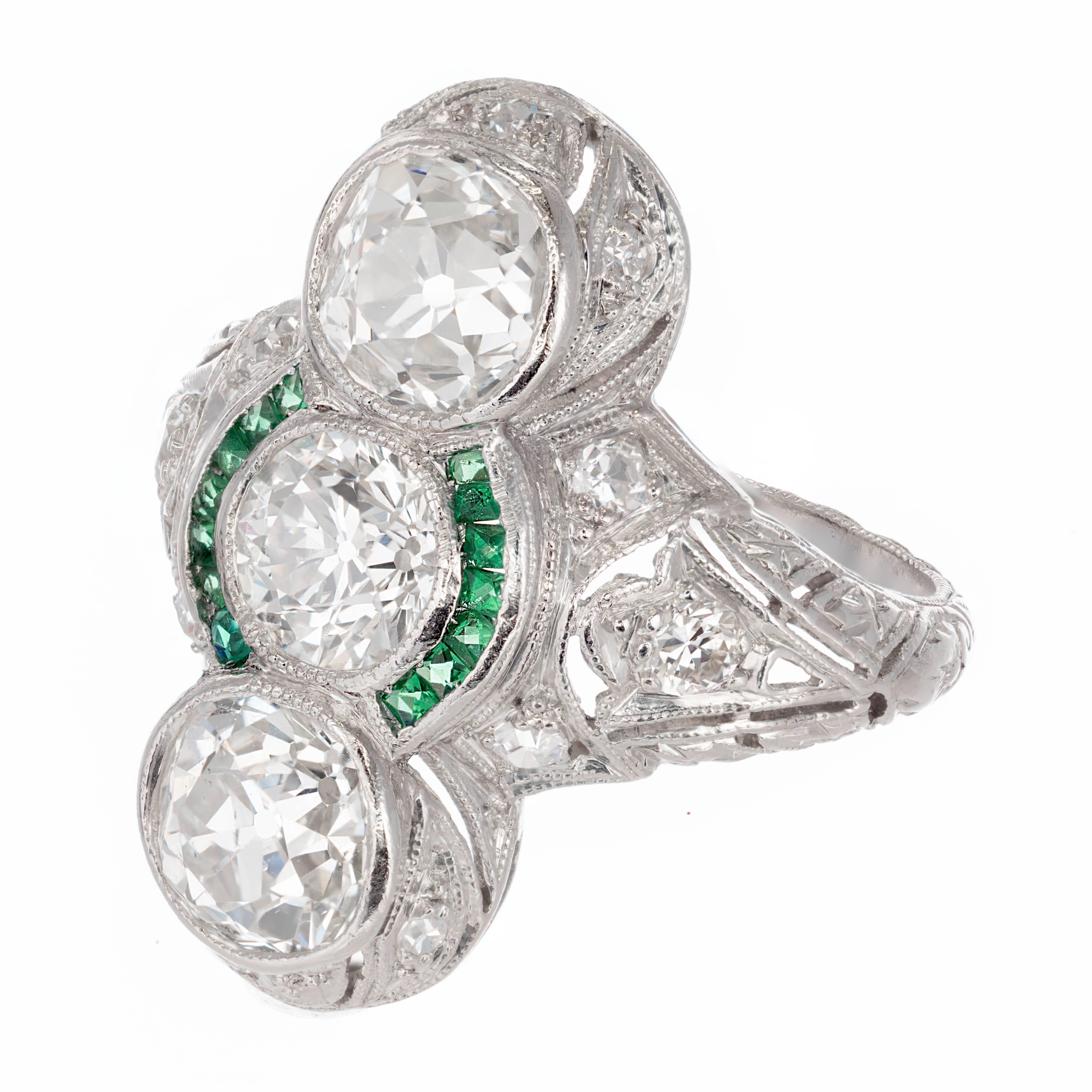 Handmade original Art Deco three-stone diamond and emerald cocktail ring. Handmade piercing, hand engraving and wonderful bright sparkly old European cut diamonds with a genuine Emerald halo. Circa 1910.

1 old European cut center diamond, approx.