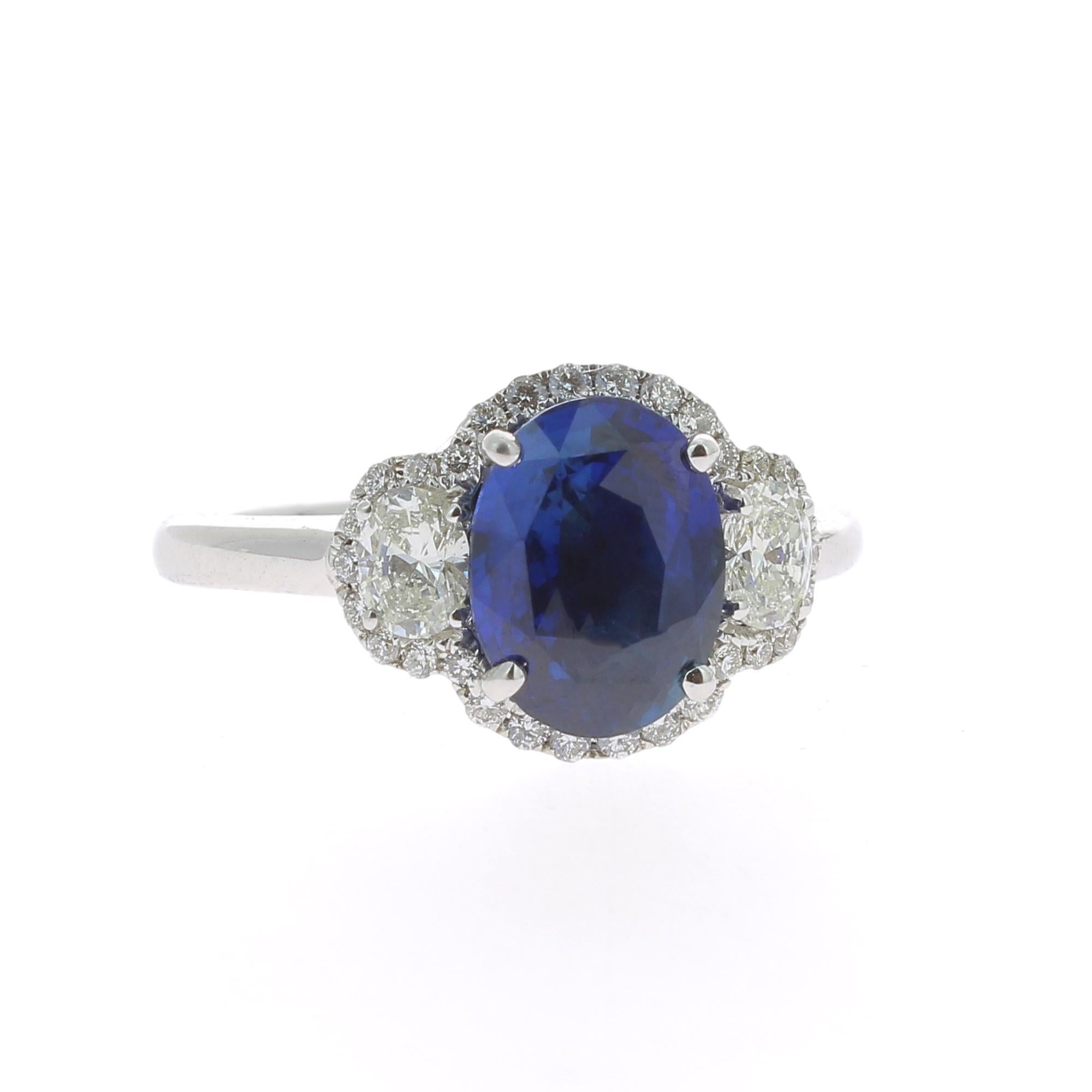 An amazing Blue Sapphire Ring flanked on each side by a single Oval Diamond and surrounded by an halo of Round Diamond.
The total weight of the Sapphire is 2.77 Carats, the gemstone is certified as a Blue Standard Heat Only Sapphire. 
The Oval