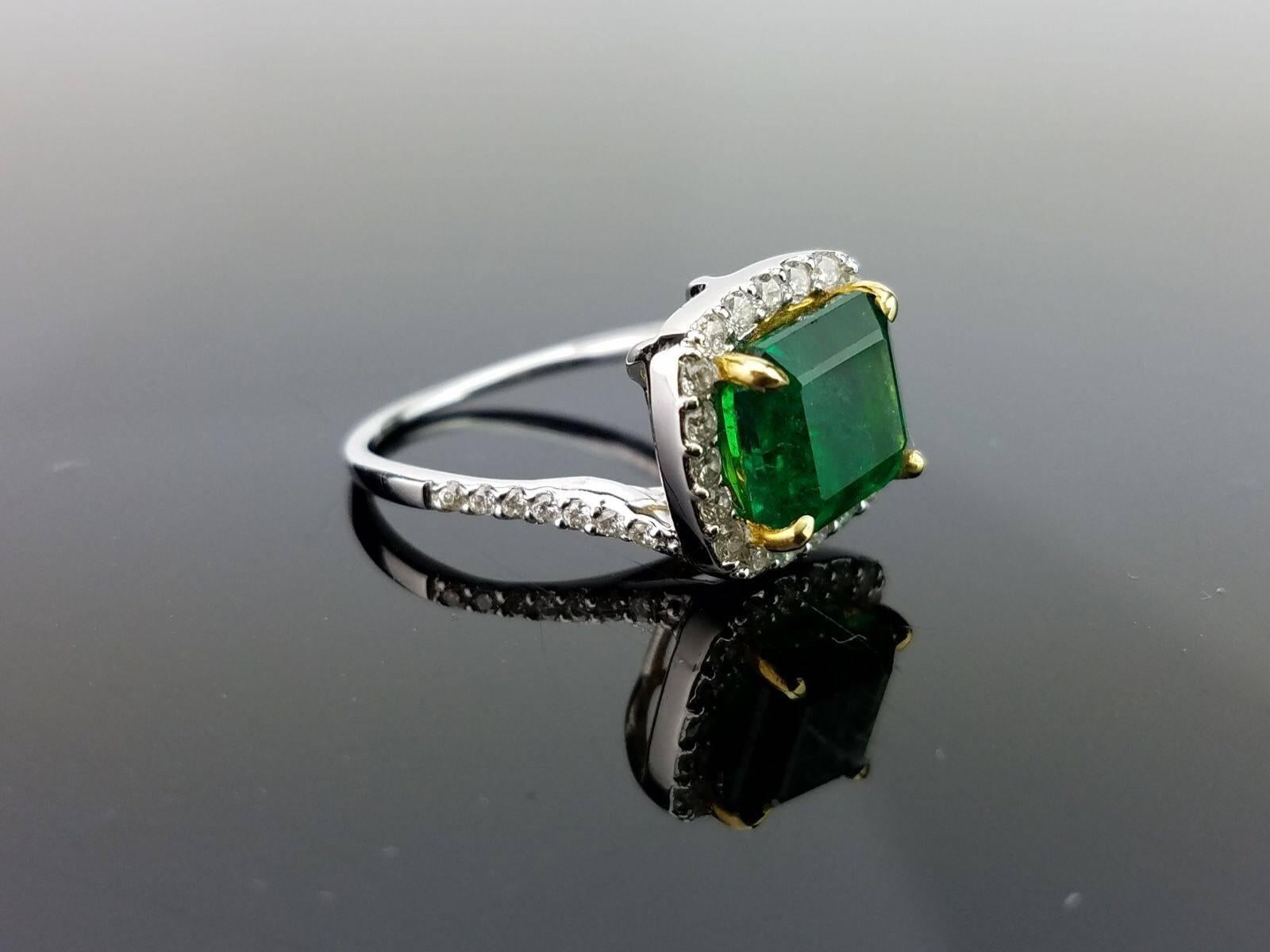 An elegant and simple cocktail ring using a lustrous emerald cut Zambian Emerald centre stone surrounded by brilliant cut white Diamonds, all set in 18K white and yellow gold. 

Stone Details: 
Stone: Zambian Emerald
Carat Weight: 2.77