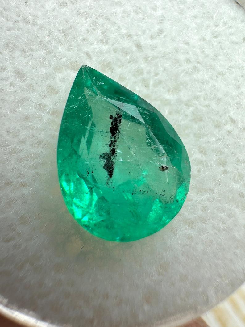 Stone: Emerald
Weight: 2.77-carats
Shape: Pear Cut
Clarity: Transparent, Visible Carbon
Luster: Very Good
Color: Medium Bluish Green
Measurements: 11.38mm x 8.31mm x 4.97mm
Geographic Origin: Colombia
Treatment: Natural, Oiling

Comments: Due to
