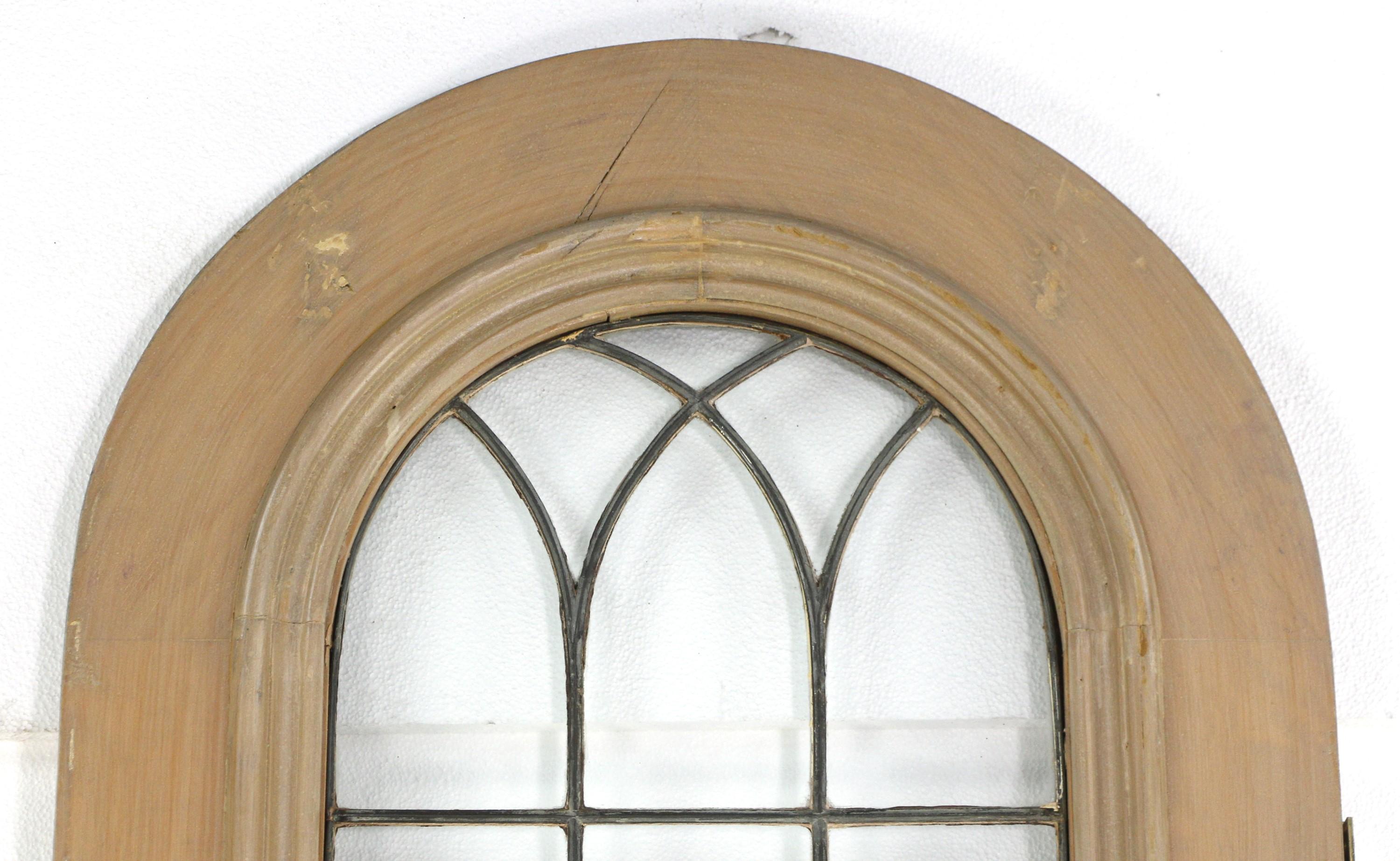 Wood door with an arched top and finished in a light color stain. The window part is divided into 21 leaded clear glass panes. The bottom of the door features a single wood panel. Minimal chips and some cracks in the wood frame. Please see the