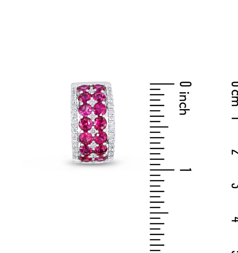This ring has fourteen round rubies set in a double row, totaling 2.78 carats. A row of round white diamonds decorates the top and bottom of this design, with additional diamonds set between the rubies. Total diamond weight 0.45 carats. Set in 14k