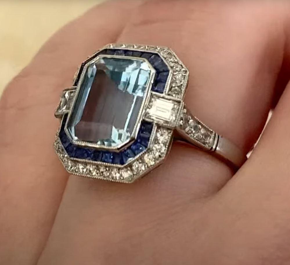 This exquisite geometric gemstone ring showcases a mesmerizing, natural emerald-cut aquamarine, weighing approximately 2.70-carats. Its crisp, ice-blue hue is beautifully complemented by a meticulously hand-crafted platinum setting. Designed with a