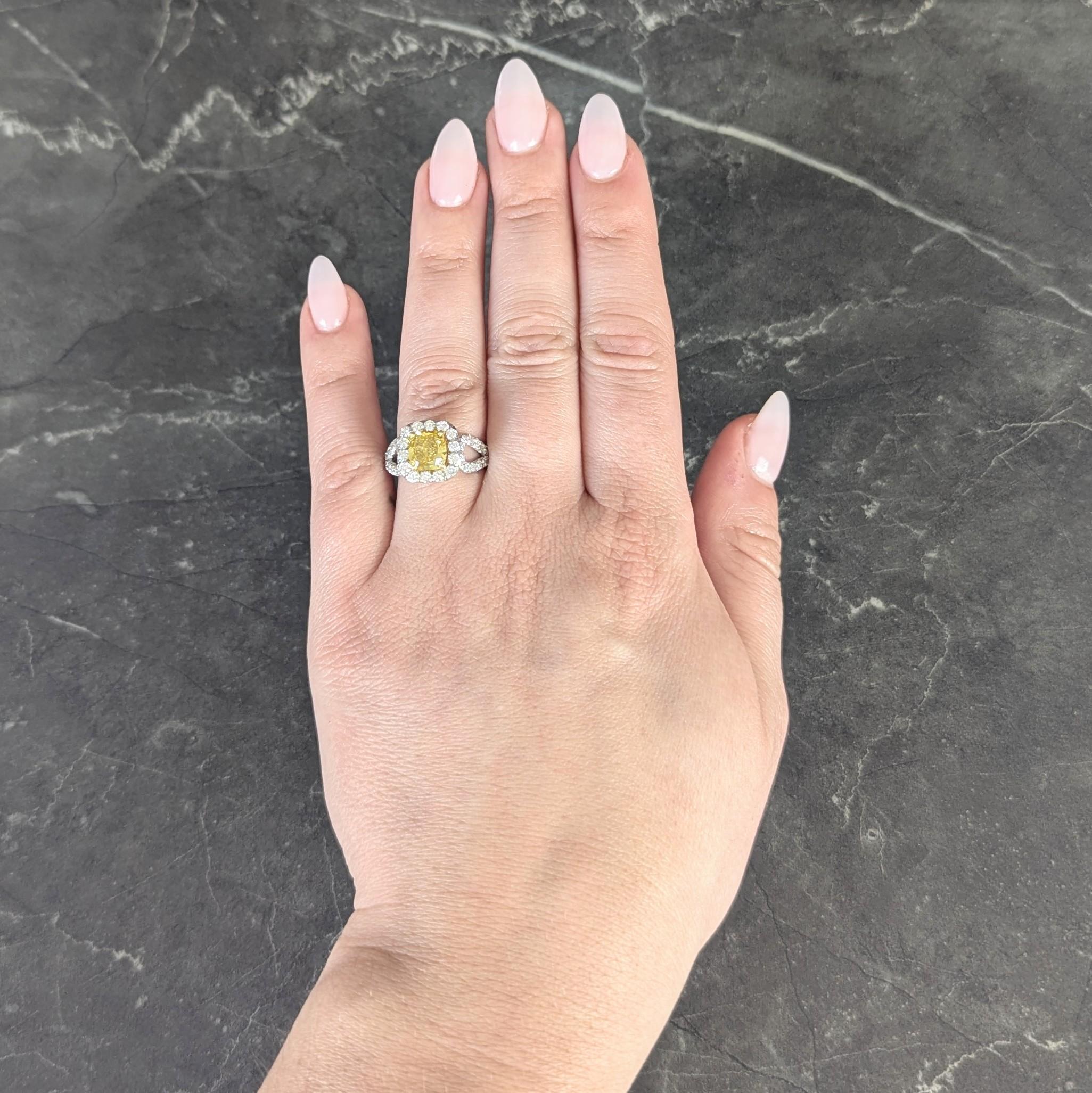 Centering a mixed cushion cut diamond weighing 1.69 carats - fancy deep yellow in color with I1 clarity
Prong set in a yellow gold basket with a platinum halo surround and looped open shoulders
Prong set throughout with round brilliant cut