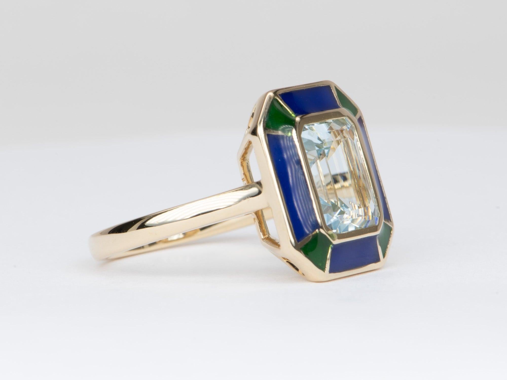   This exquisite statement ring is crafted with a stunning 2.79ct crystal-clear aquamarine center and surrounded by a halo of jewel-toned green and blue enamel. Set in 14K yellow gold, this one-of-a-kind ring will be the perfect way to show your