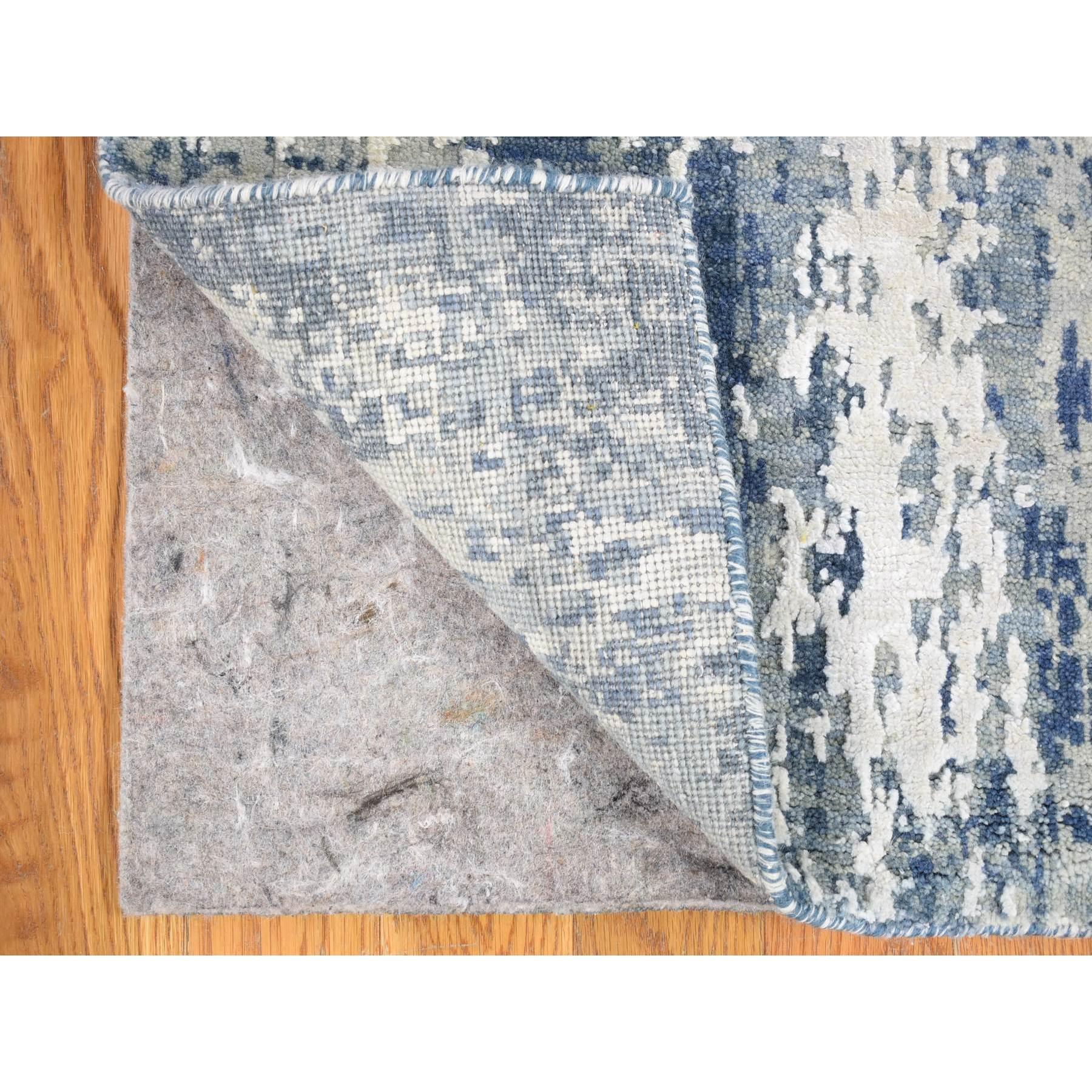 Il s'agit d'un véritable tapis d'Orient, unique en son genre, noué à la main, en laine et soie véritable, avec un design abstrait bleu. Il a été noué pendant des mois et des mois selon des techniques de tissage séculaires par des artisans