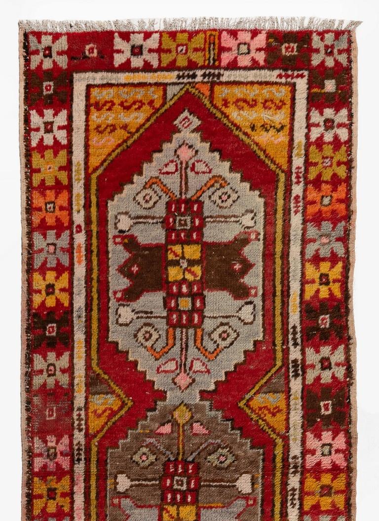 Vintage runner rug from Turkey with finely hand-knotted even medium wool pile on wool foundation featuring linked geometrical medallions in taupe gray and light blue in a tomato red field and angular star motifs in a rainbow of soft and vivid hues