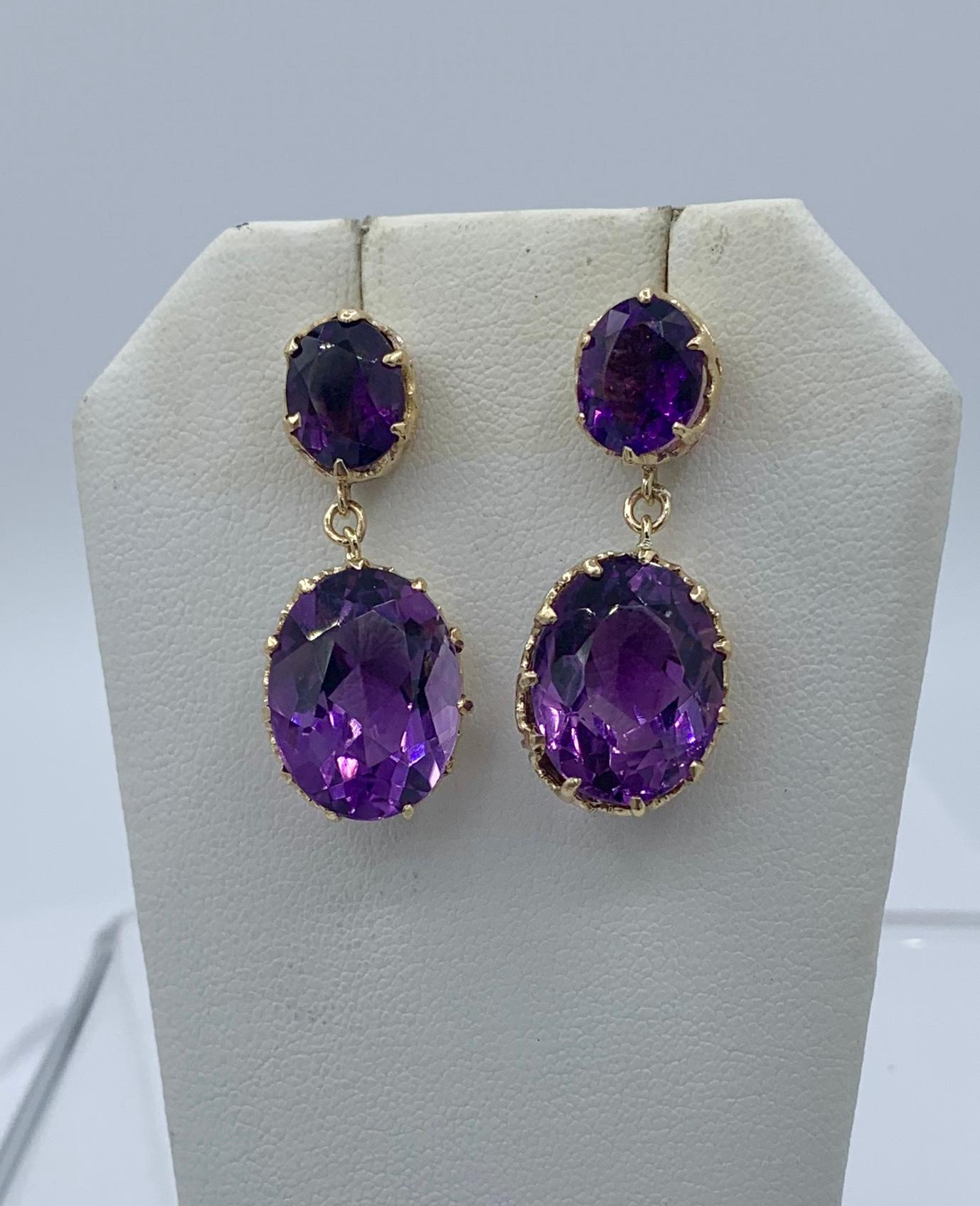 A STUNNING PAIR OF EARRINGS WITH 28 CARATS OF ANTIQUE SIBERIAN AMETHYSTS.  THE DROP DANGLE PENDANT EARRINGS ARE 1 3/8 INCHES IN LENGTH.  THE AMETHYSTS ARE SET IN BEAUTIFUL 14 KARAT GOLD WITH A CROWN MOTIF SETTING ENCIRCLING THE JEWELS.  THE CUT,