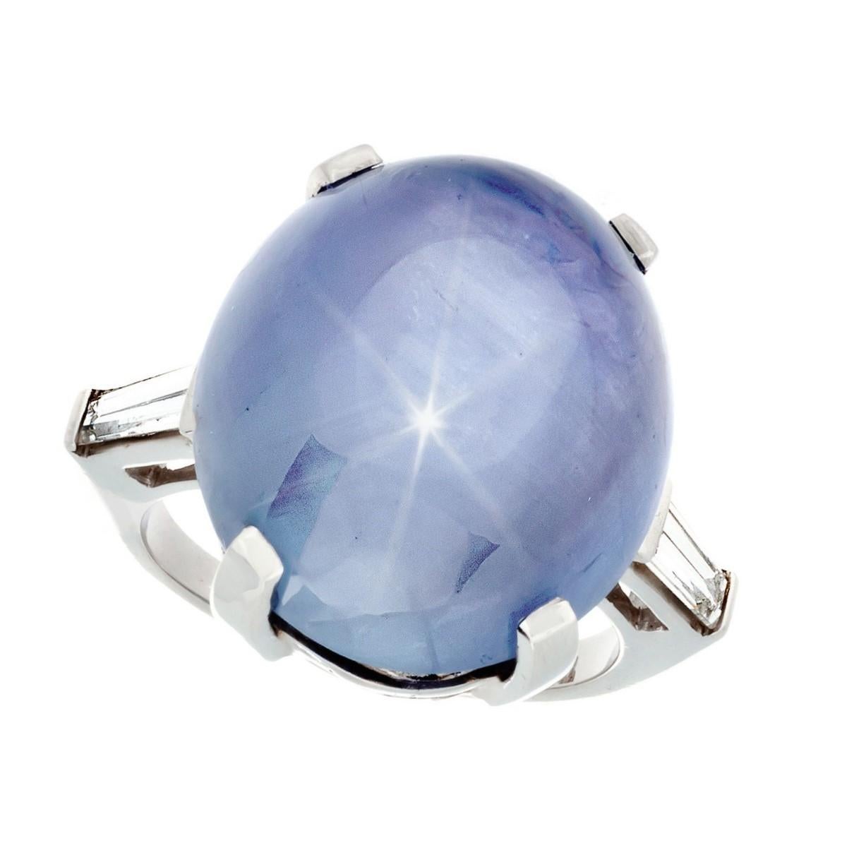 Vintage Platinum Blue Star Sapphire and Diamond 3-Stone Ring; The ring is set with 1- Oval Cabochon Cut Star Sapphire weighing 28.08 Carats.  The Ring is Further Set With 2-Taper Baguette Cut Side Diamonds to total approximately  0.30 Carat . With F