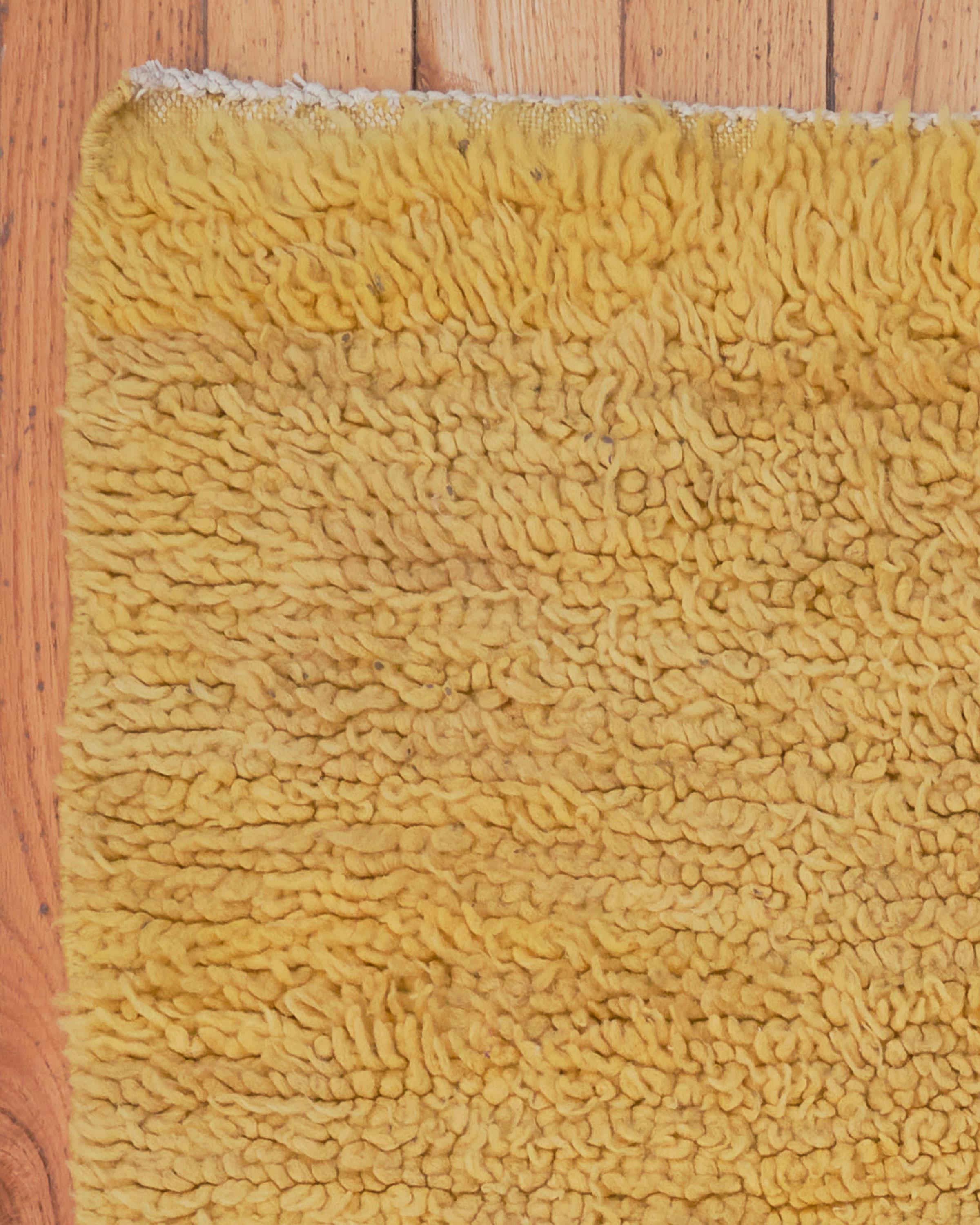 The Alyssum rug is a charming vintage Moroccan piece, handwoven with care by Berber artisans. Made from 100% natural sheep’s wool, this light yellow rug offers a soft and inviting texture that brings warmth and comfort to any space. Its minimalist