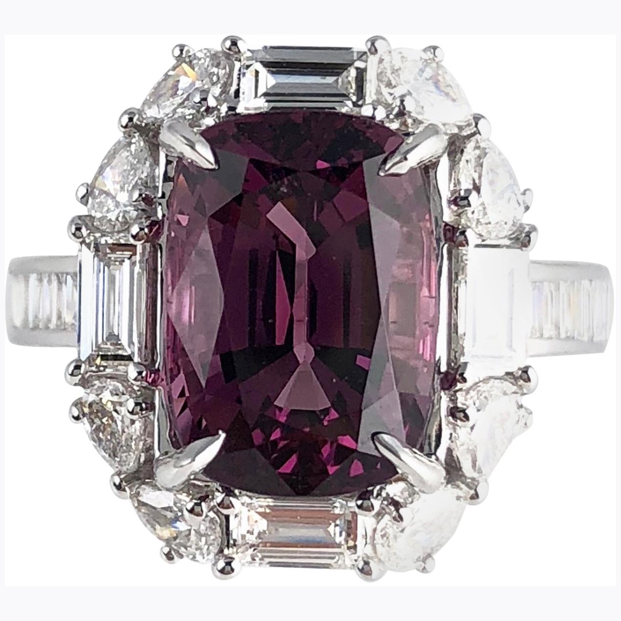 (DiamondTown) This beautiful handcrafted ring features a 4.92 carat cushion cut Raspberry Garnet center, surrounded by a halo of baguette and pear shape diamonds. Additional baguette diamonds trace down the side shank, bringing the total diamond
