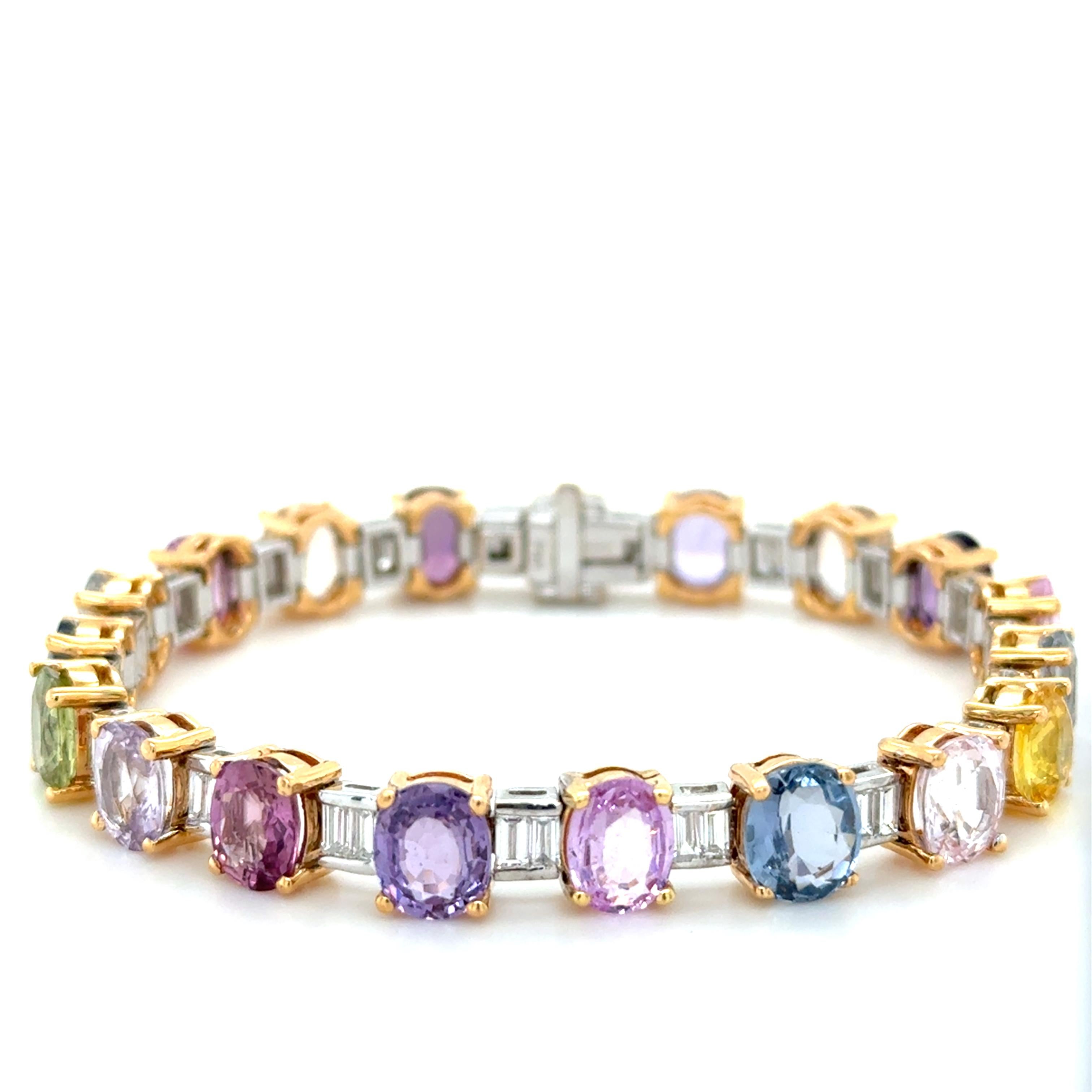 This colorful bracelet is designed as a series of graduated multicolored sapphires in hues of pink, green, blue and yellow weighing approximately 28.00 carats total, alternating with baguette-cut diamond two-stone sections weighing approximately