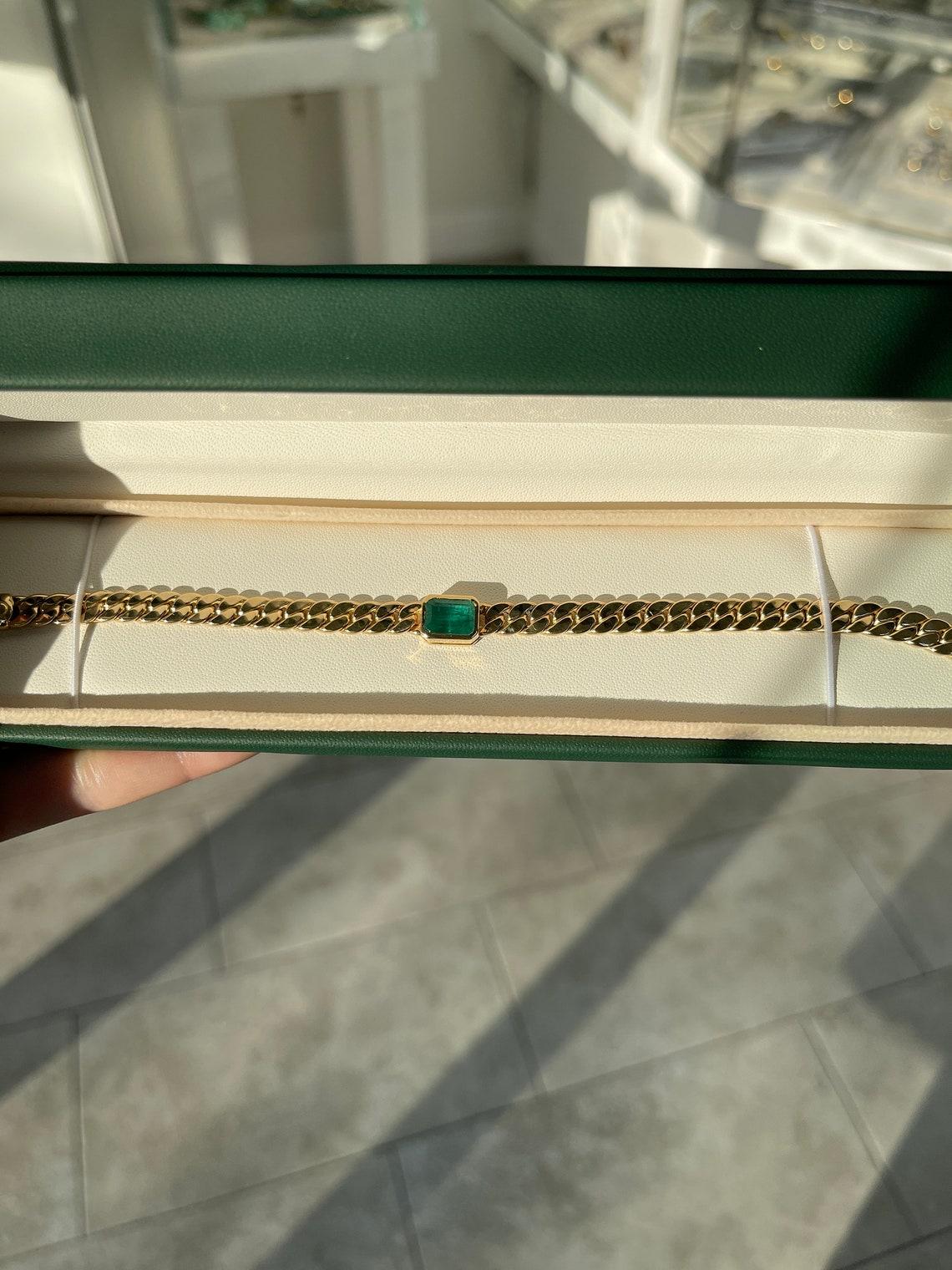 Ce bracelet en émeraude présente une émeraude de 2,80 carats sertie en chaton, orientée d'est en ouest. L'émeraude présente une couleur vert foncé luxuriante. Le bracelet lui-même est fabriqué en or 14k, avec un style plat mesurant 6,30 mm de