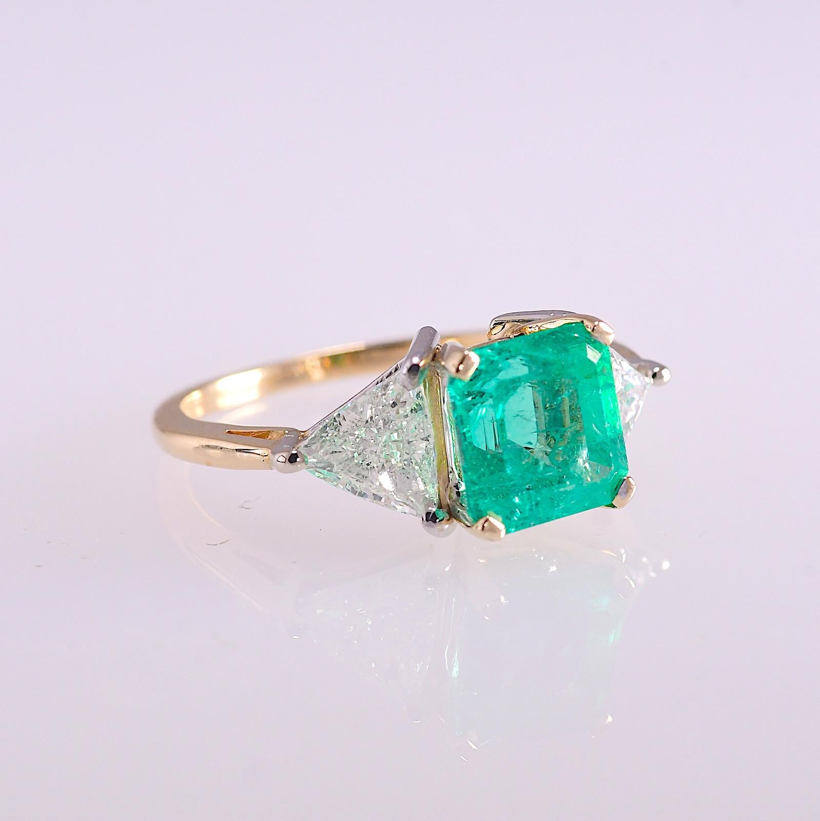 This classic style ring contains a 2.82 carat square emerald cut emerald with two triangular brilliant diamonds totaling 1.40 carat.
The emerald is bright and vibrant with a bluish green hue. The diamonds are SI1-SI2 clarity and G-H color. The ring