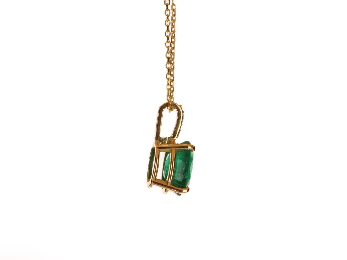 Featured here is a stunning oval emerald & diamond accent necklace in fine 18k yellow gold. Displayed in the center is a deep DARK rich green emerald accented by a simple four-prong gold mount, allowing for the emerald to be shown in full view. This