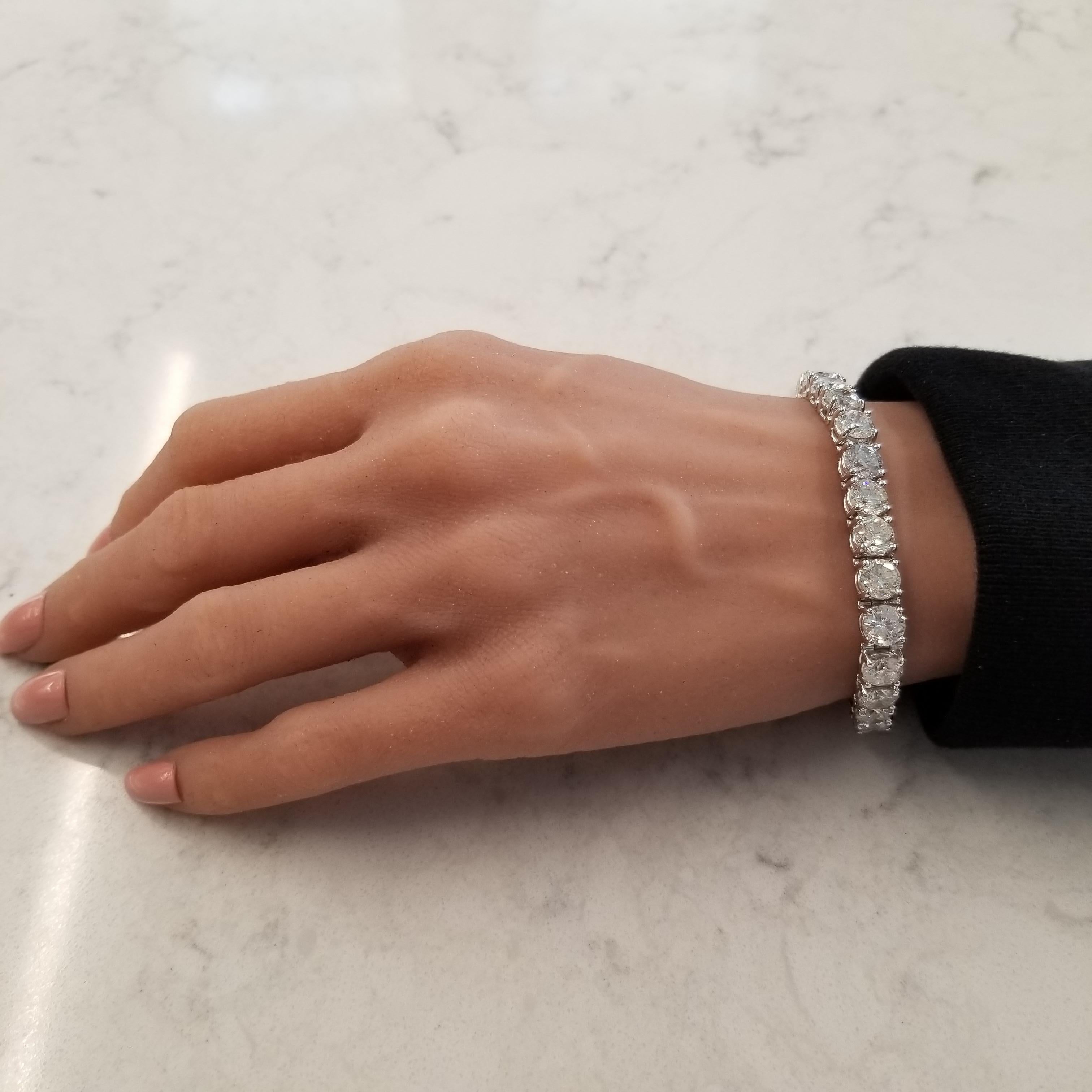 Designed in 18 karat white gold, this gorgeous classic tennis bracelet features a total of 28.42 carats of 27 sparkling round brilliant cut diamonds that are basket prong set around it, eternity style. This sophisticated tennis bracelet is finished