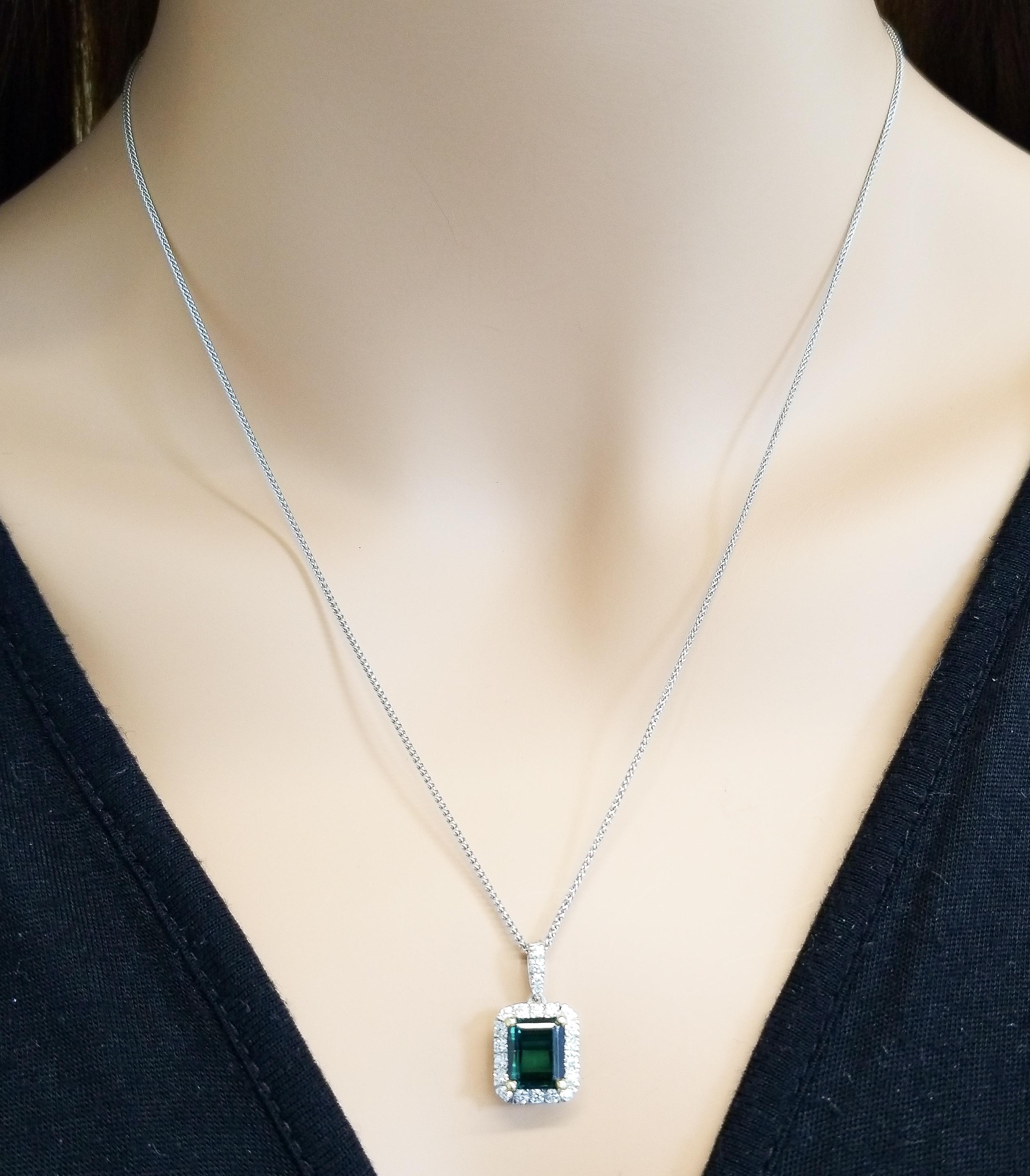 Finish your look with a touch of elegance wearing this gorgeous geometric pendant. One 2.85 carat emerald cut bluish-green tourmaline takes center stage in rich yellow gold accented prongs and is surrounded by round brilliant cut diamonds that are