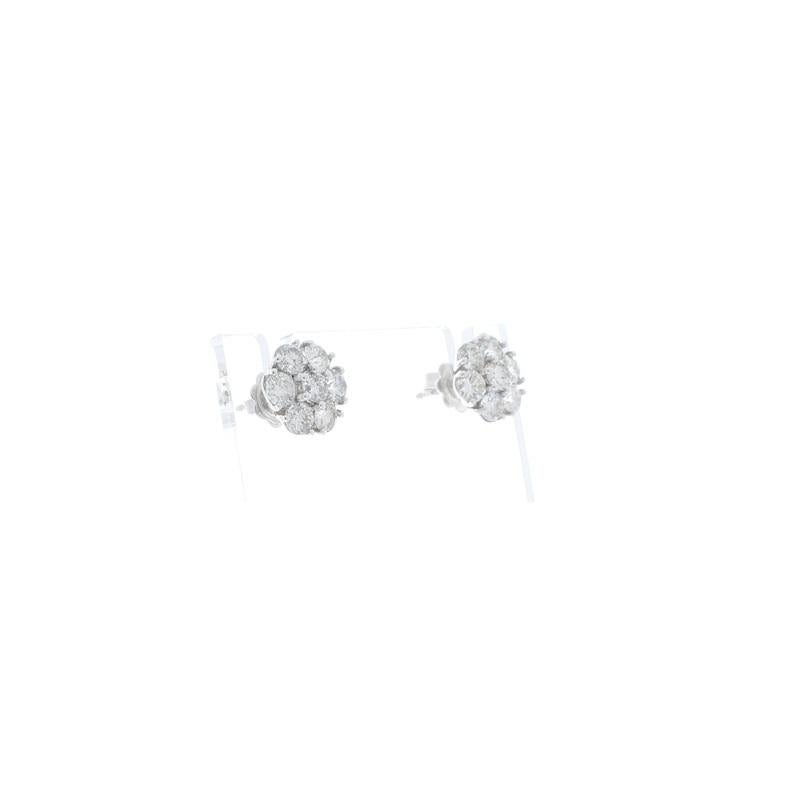 These are elegant cluster earrings that feature 14 round brilliant cut diamonds carefully prong-set into scintillating flower shapes, totaling 2.85 carats. Designed in brightly polished 14K white gold, these stunning studs sit securely on the ears