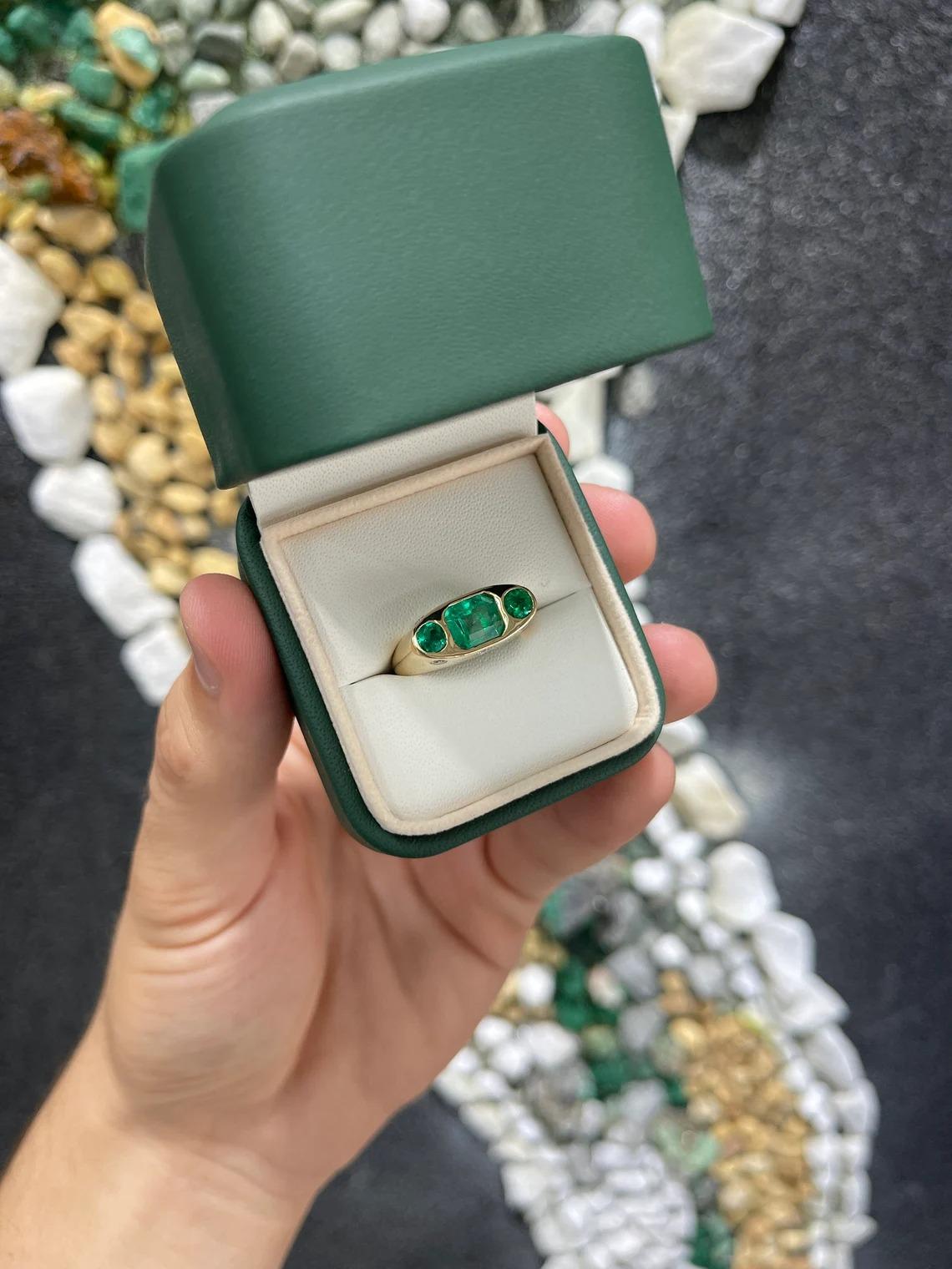 A glamorous, fine-quality Colombian emerald and diamond three-stone ring. The center stone features a striking 1.94-carat, emerald-cut Colombian emerald set east to west. This stone displays a stunning vivid green color, close to excellent eye