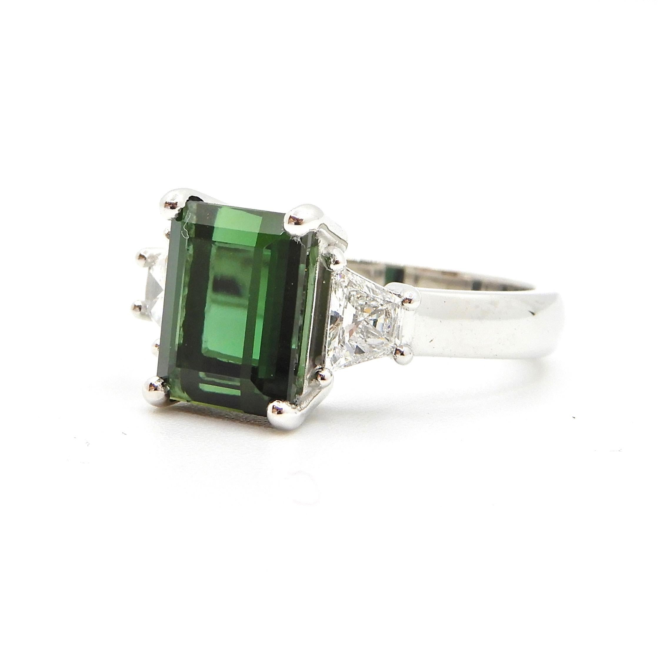 This vivid green, 2.86 Carat Green Tourmaline and Diamond Cocktail Ring is set in 18 carat Australian White Gold.  The rounded band supports a central 4 claw set, perfect shade of green, emerald cut Tourmaline.  Flanked by G SI trapezoid cut