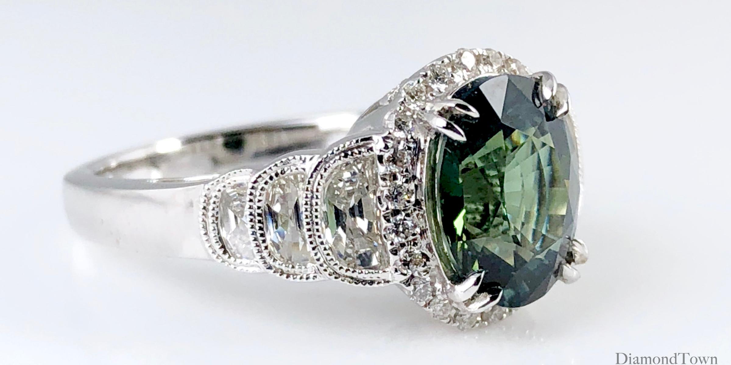 This gorgeous GIA Certified ring features a 2.86 carat oval cut Forest Green Sapphire center, surrounded by a halo of round white diamonds. Each side shank features 3 half moon diamonds of descending size, decorated with detailed milgrain work.

GIA