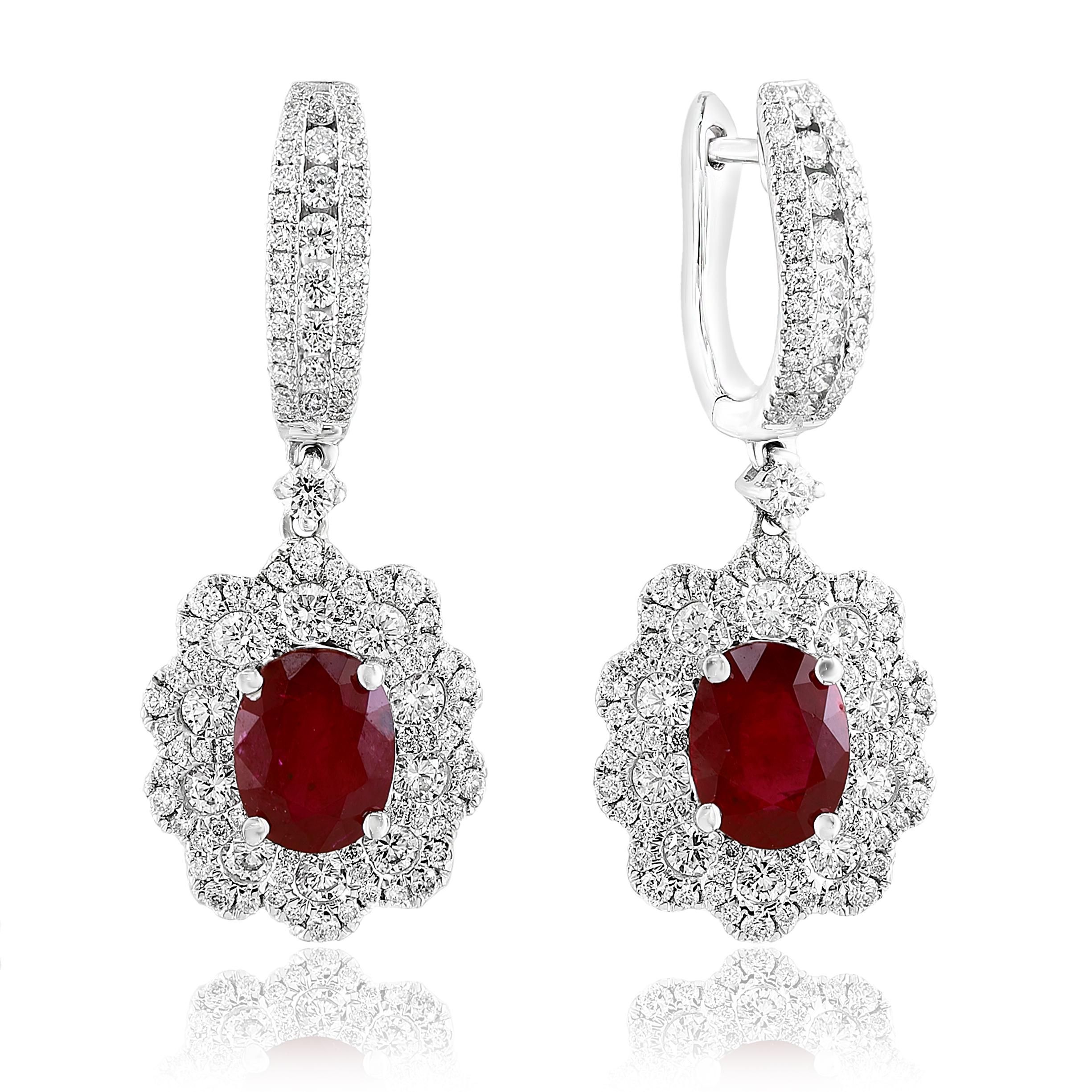 Dangle earrings featuring Oval shape red Rubies weighing 2.86 carats total, surrounded by two rows of round brilliant diamonds in a flower design. 194 Accent Diamonds weigh 0.98 carats and 20 accent diamonds weigh 0.79 carats in total. Made in 18