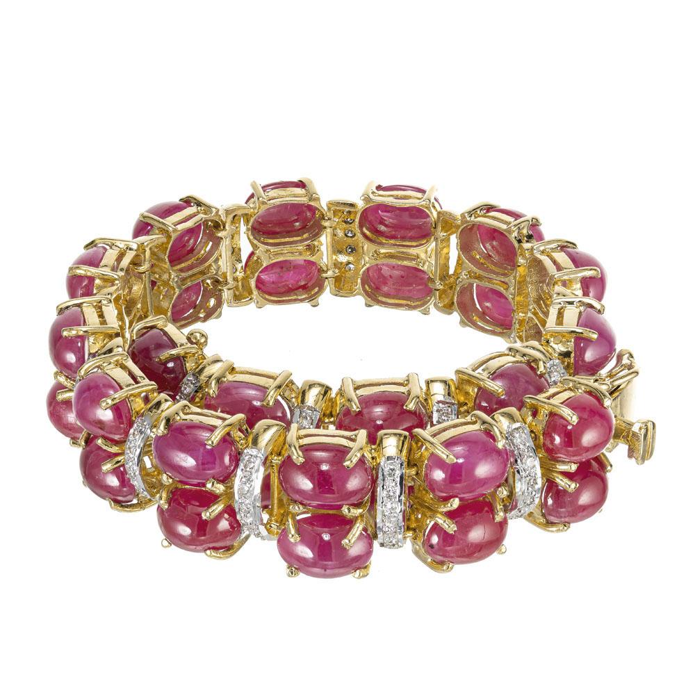 Ruby and diamond handmade hinged bracelet.  34 oval cabochon oval rubies set in 20k yellow gold. Separated by rows of round diamonds, set in 20k white gold. 6.75 inches long. 

34 cabochon oval rubies approx. total weight 28.60cts.
80 round diamonds