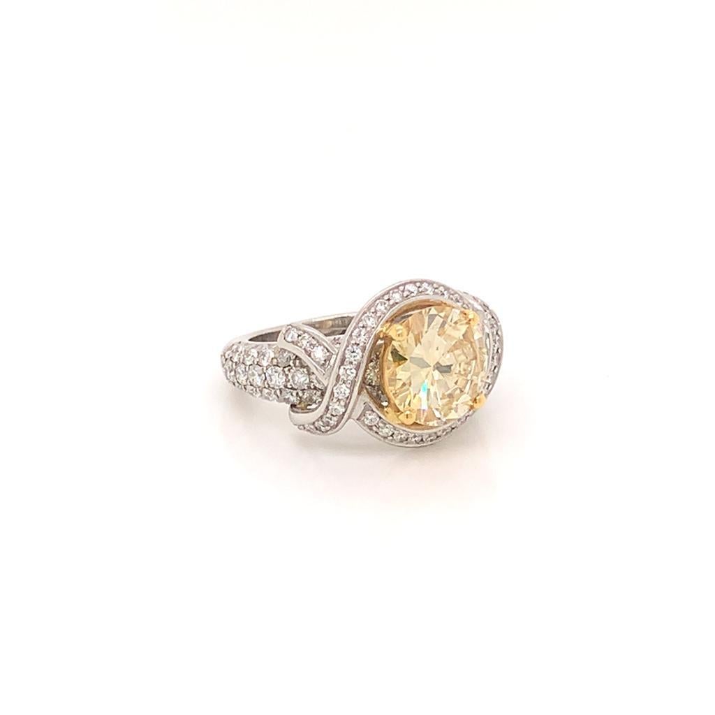This exquisite ring is made of a Magnificent Round Brilliant Yellow Diamond, weighing 2.87 Carats, and Round Brilliant White Diamonds, weighing 2.75 Carats, set in 18K Yellow Gold and Platinum. Its unique design is one that makes this ring stand out
